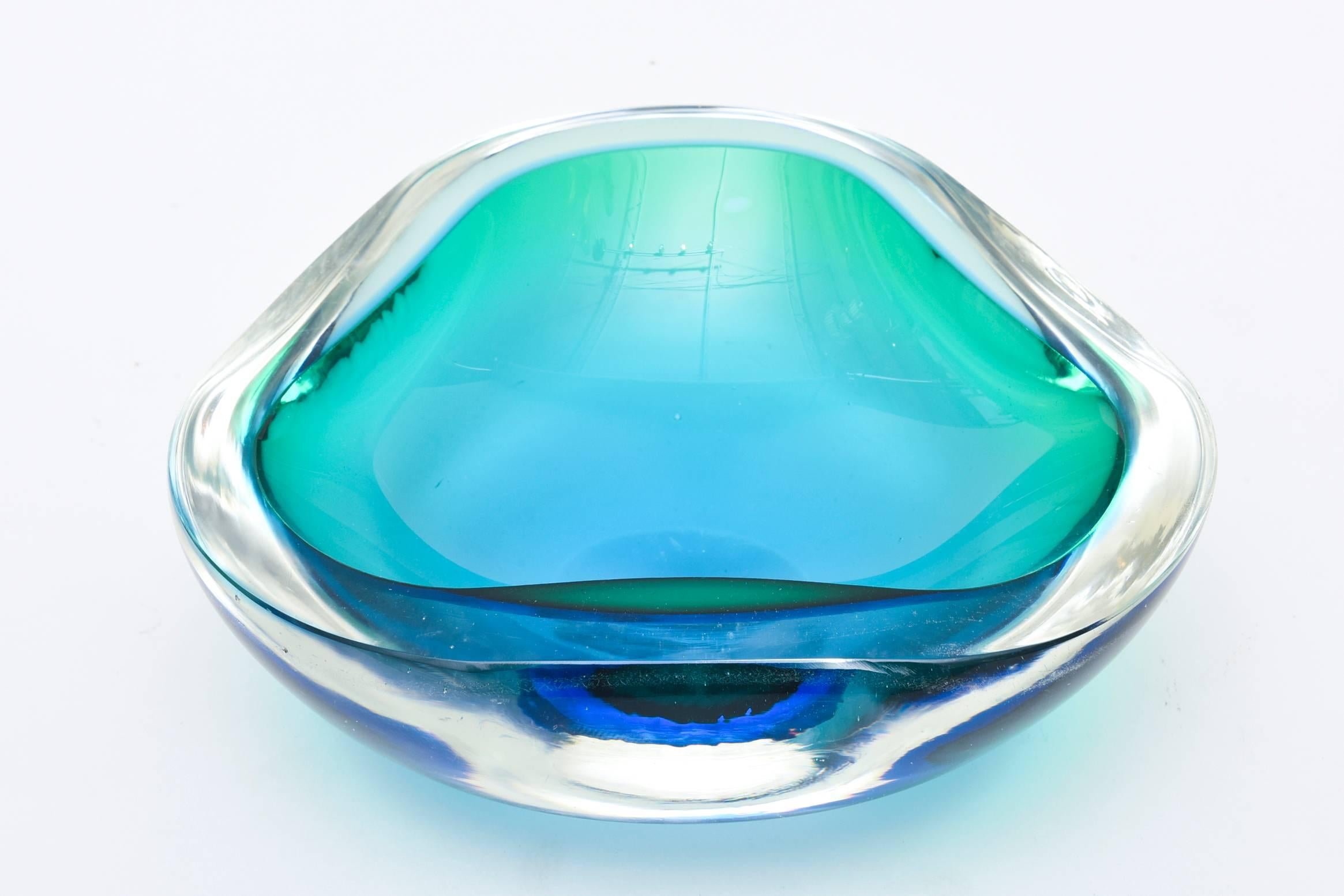 The colors of the sea dominate this luscious dynamic substantial Italian Murano glass bowl by Seguso. It is layered with Sommerso technique of glass in turquoise, sea greens to royal blue. The shape has a somewhat irregular form that is semi heart