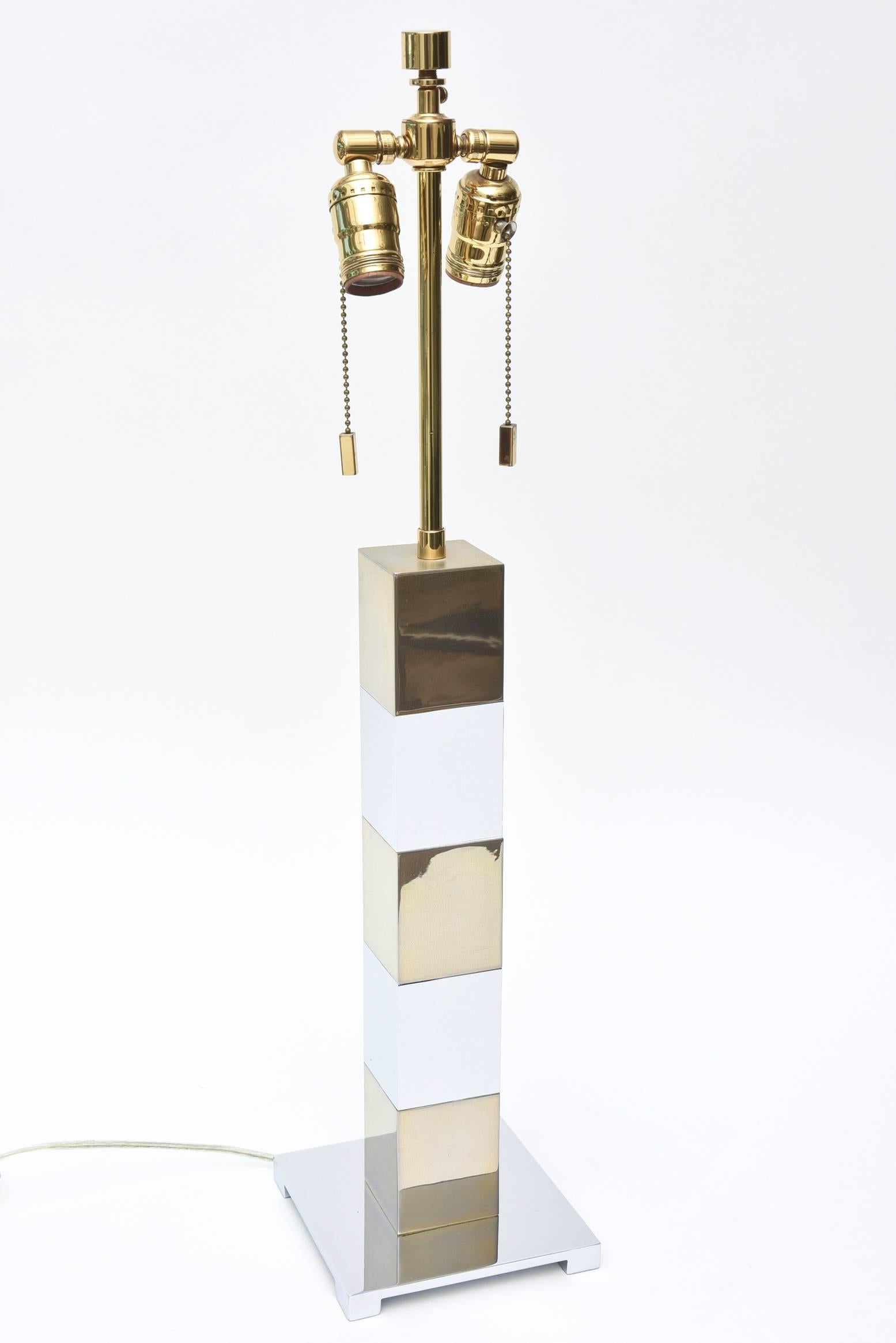 This modern table or desk lamp is in the style of Karl Springer. It has alternating chrome and brass cubes that sits on a chrome base. There are two pull chains for the double socket with the original finial. It is 28.5