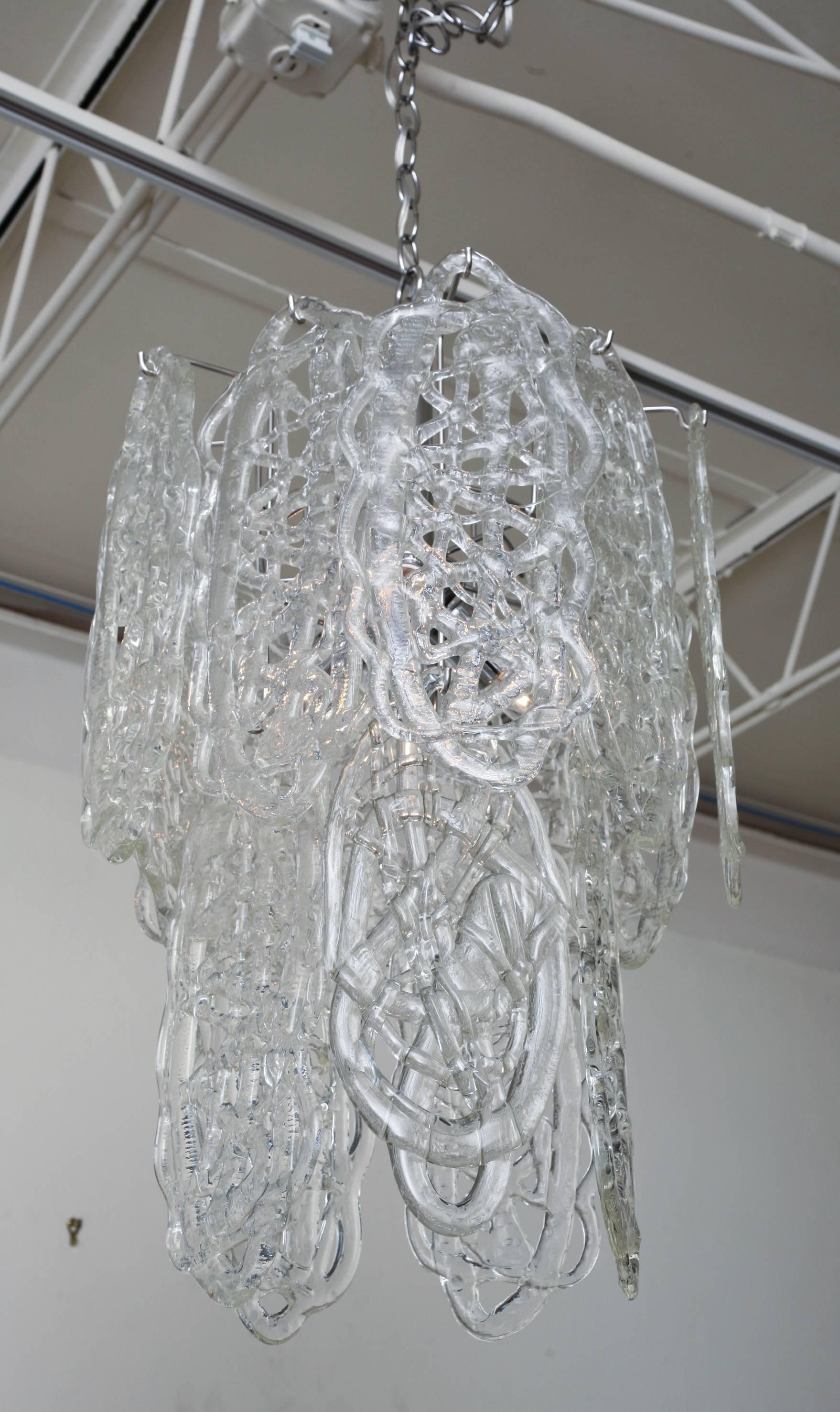 This gorgeous Italian Murano vintage Mazzega chandelier has 15 white pretzel like forms of fused glass pendants hanging to create an abstract design and form. The cage has all been re-chromed and the chain is two feet. The pendants look like a weave