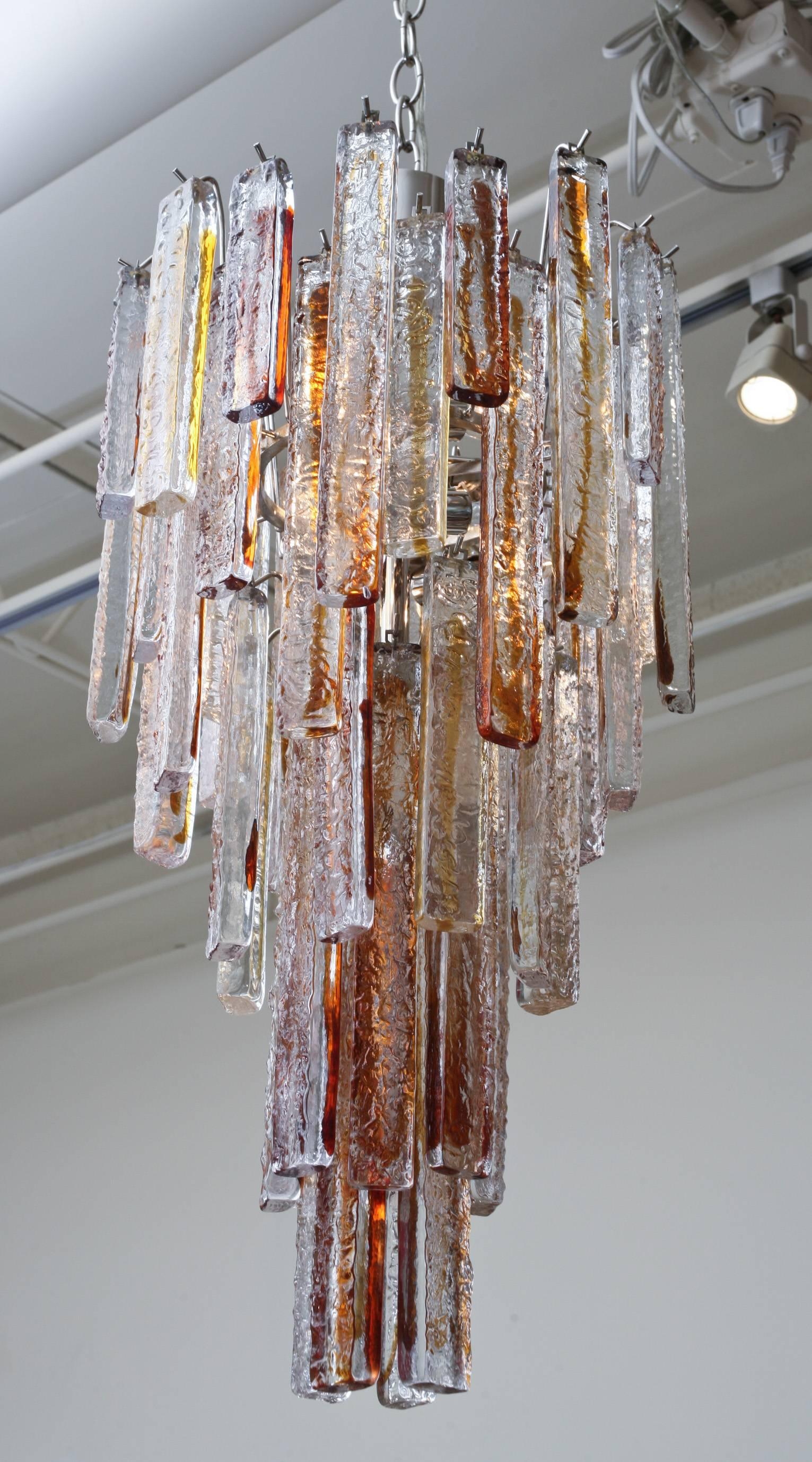 This stunning Italian Murano vintage Mazzega glass chandelier has 53 staggered textural glass pendants hanging. It is amber and clear glass fused and is very sculptural. It has all been rewired for American lighting. The cage was redone in nickel