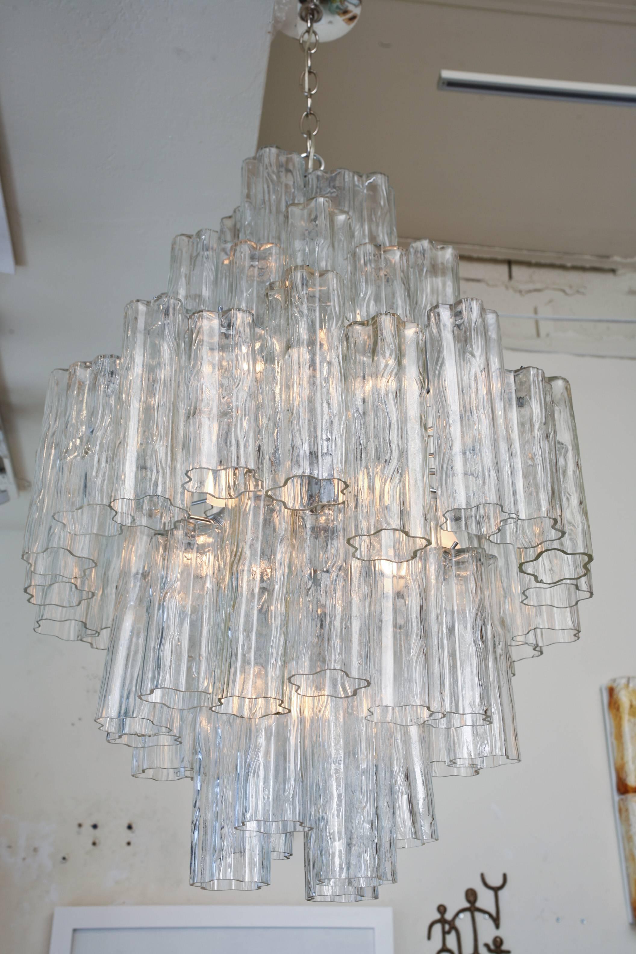 This gorgeous and substantial Venini Murano vintage chandelier has tubular hand blown glass pendants on five tiers. The widest is at the center. There are 56 pieces of textural Murano glass layered. The cage has been re-nickeled silver and rewired.