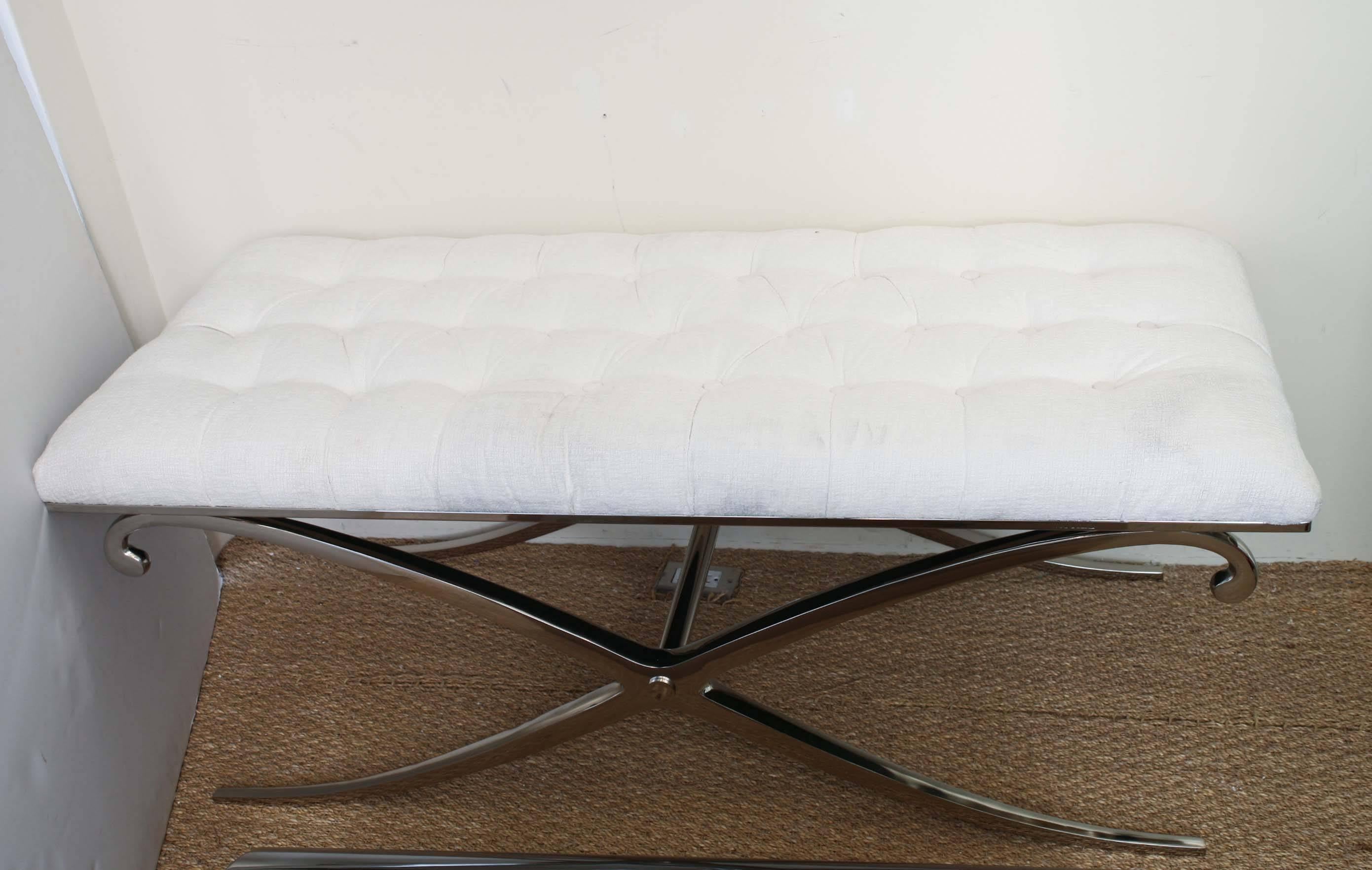 This substantial bench has inspirations of Dorothy Draper and Hollywood Regency. It is nickel silver over steel. The gracious curves of the X-frame make this so modern. The tufted upholstered top is in white. We have not re-upholstered it; that is