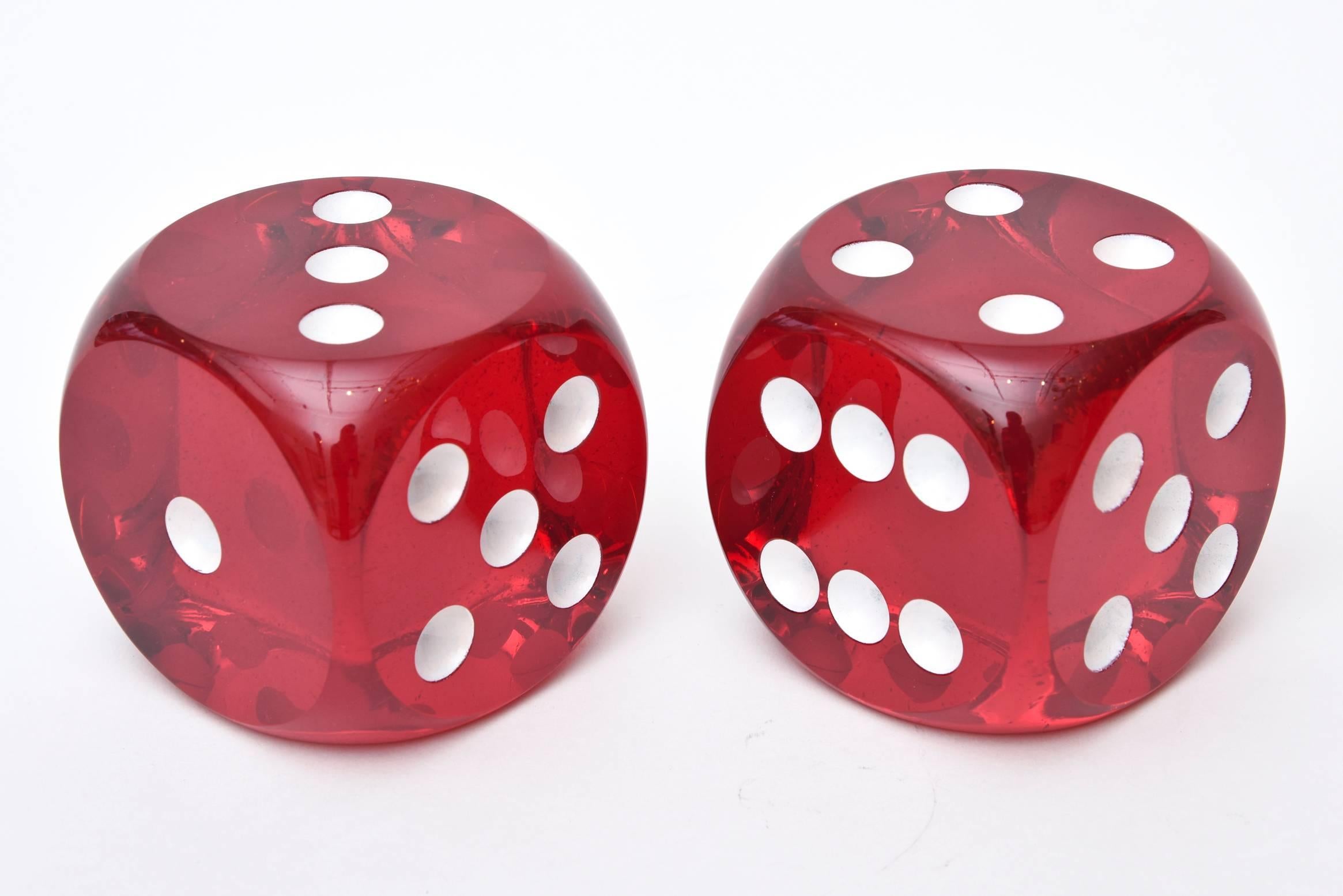 These arresting pair of red bakelite Mid-Century dice certainly make a statement in any place or room. They are large and bring theater to any setting.
Their dots are white and they have been polished.

They act as sculptures and art. Sold as a pair