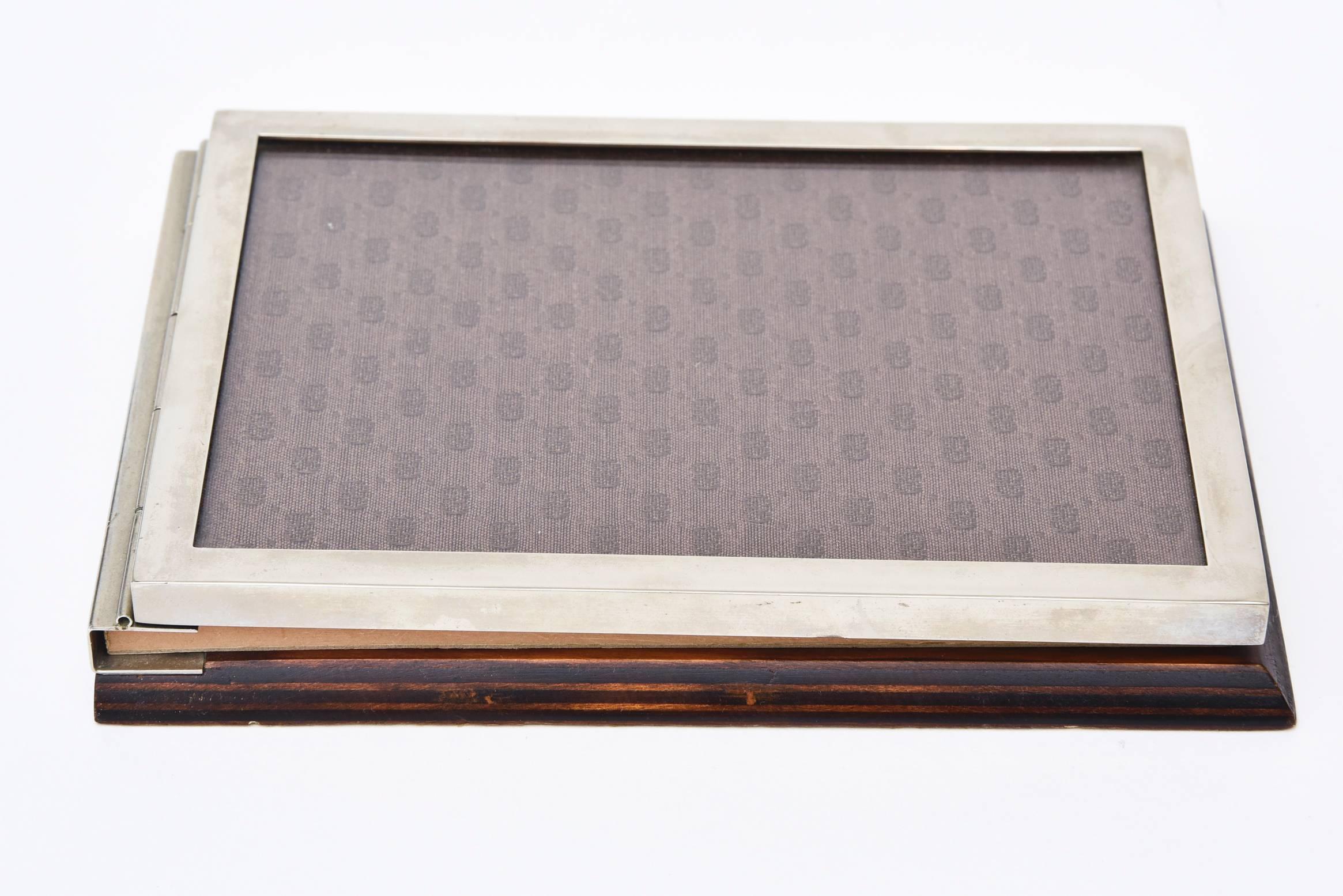 This wonderful vintage Italian signed Gucci note pad holder has wood backing with flip topnote holder and the iconic logo fabric Gucci symbols as the front. It is darker brown on lighter brown. Inside the flap is a black melamine. The original note