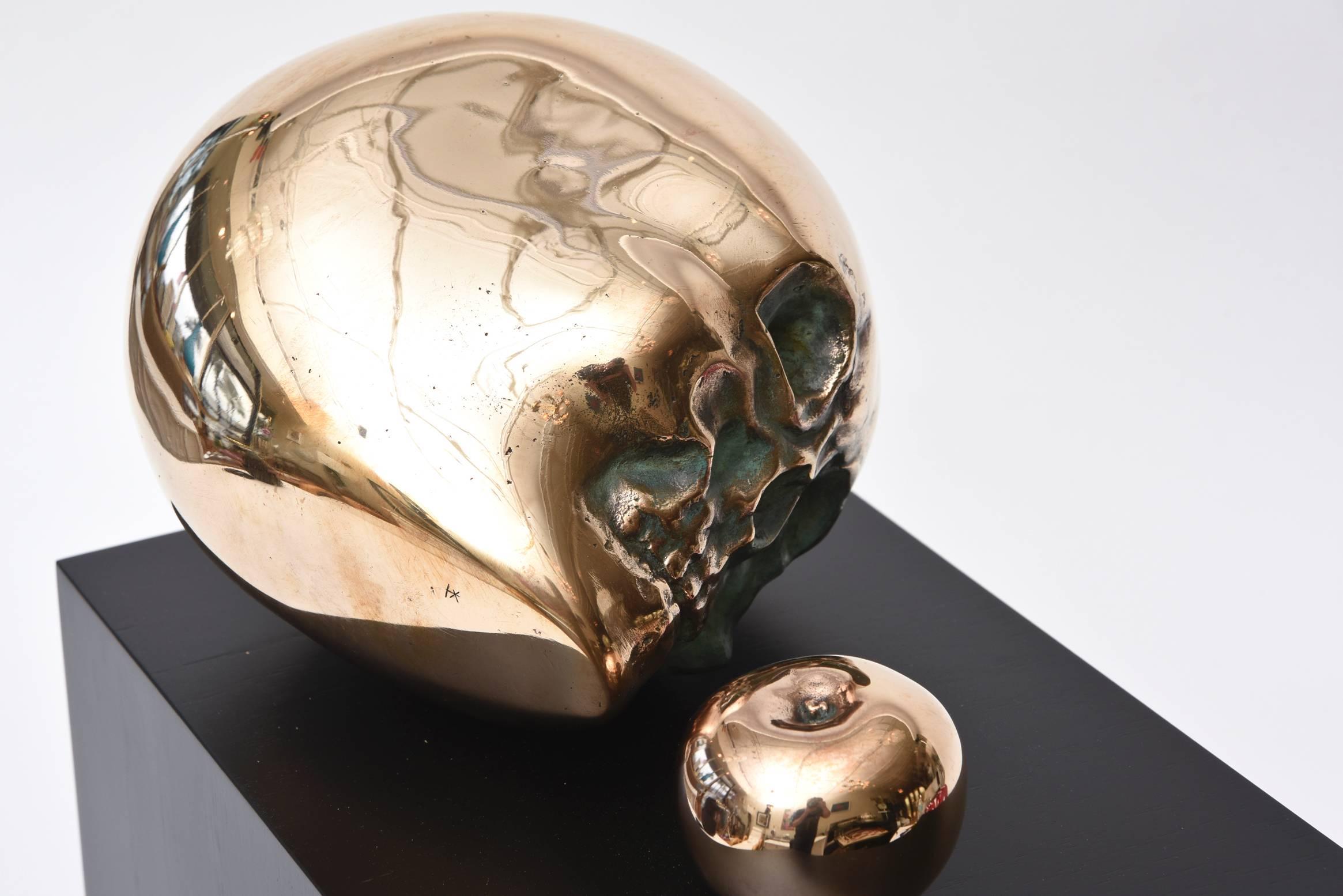 This wonderful vintage bronze sculpture is dimensional and large. The polished bronze large skull head and small apple are yin and yang. It sits on an a black stained wood original base that has been redone. It is signed inside by an unknown