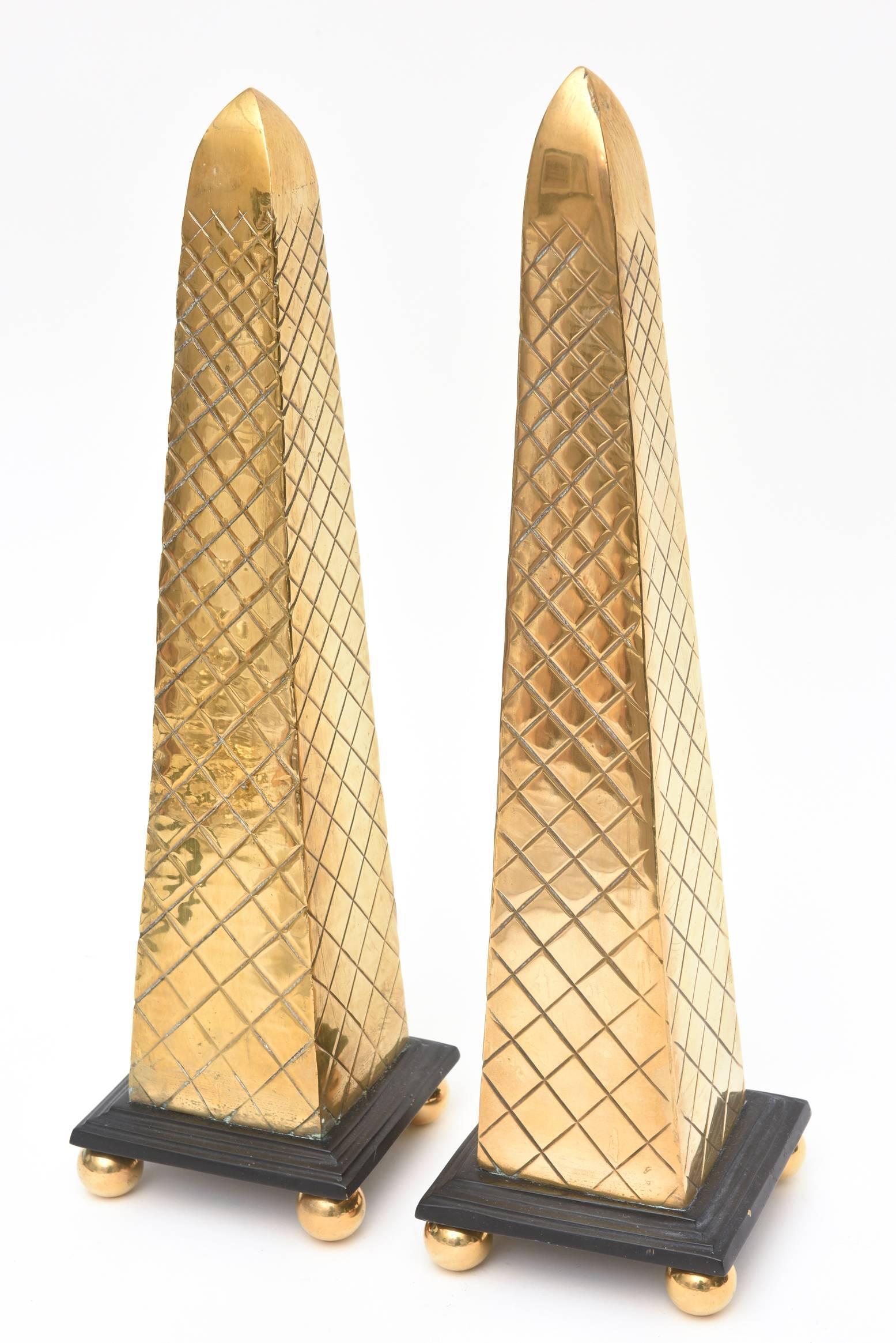 These two varying sizes of brass diamond patterned obelisks have ebonized black square bases with four ball feet. The ball feet screw on and off.
They have great weight to them. Great for flanking a mantel fireplace or as an object for a
