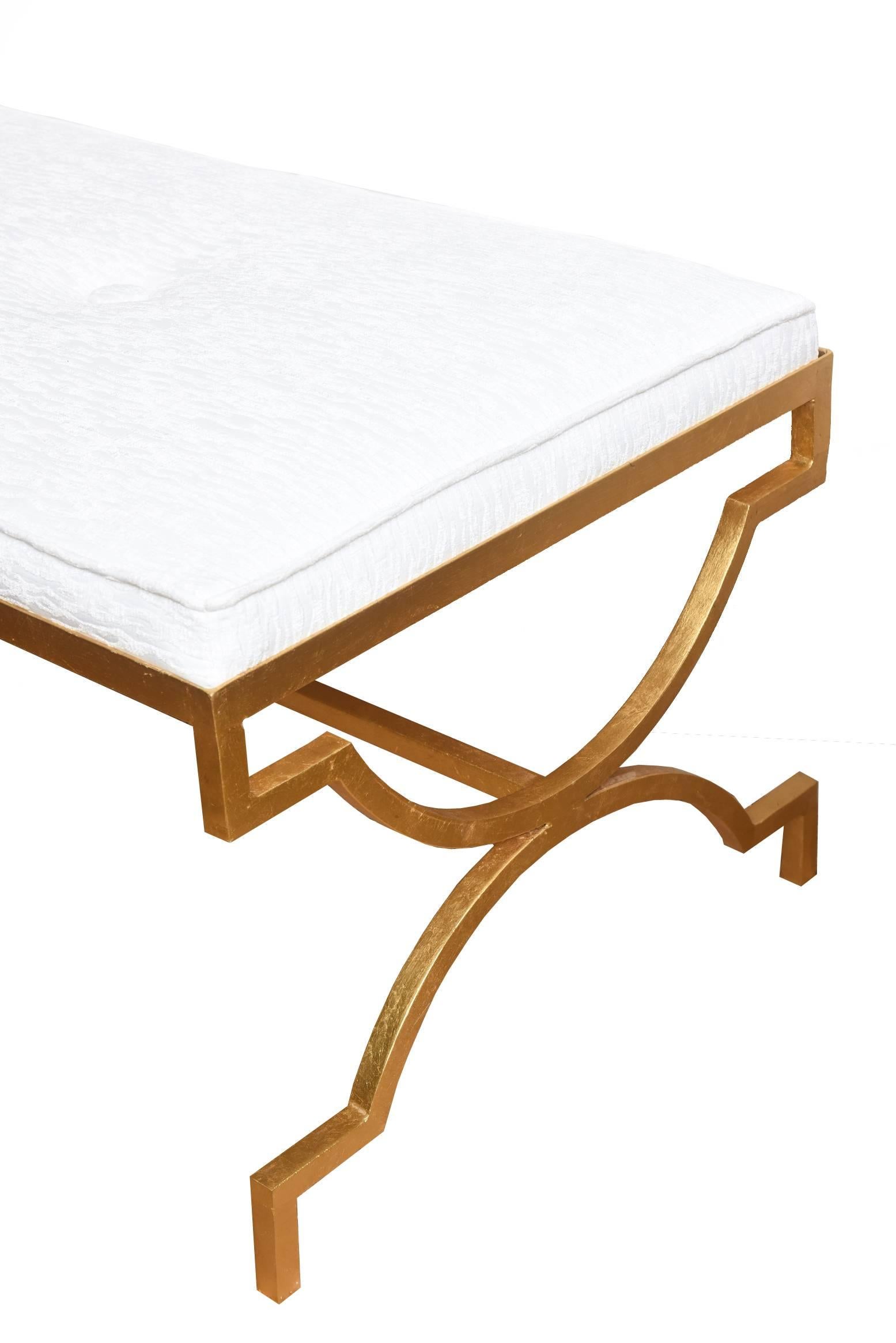 This stunning Hollywood Regency inspired Mid-Century Modern vintage Tommi Parzinger gold leafed iron bench has been totally restored. It has been newly upholstered in a white cut velvet sculptural fabric. There are three round buttons on the top.