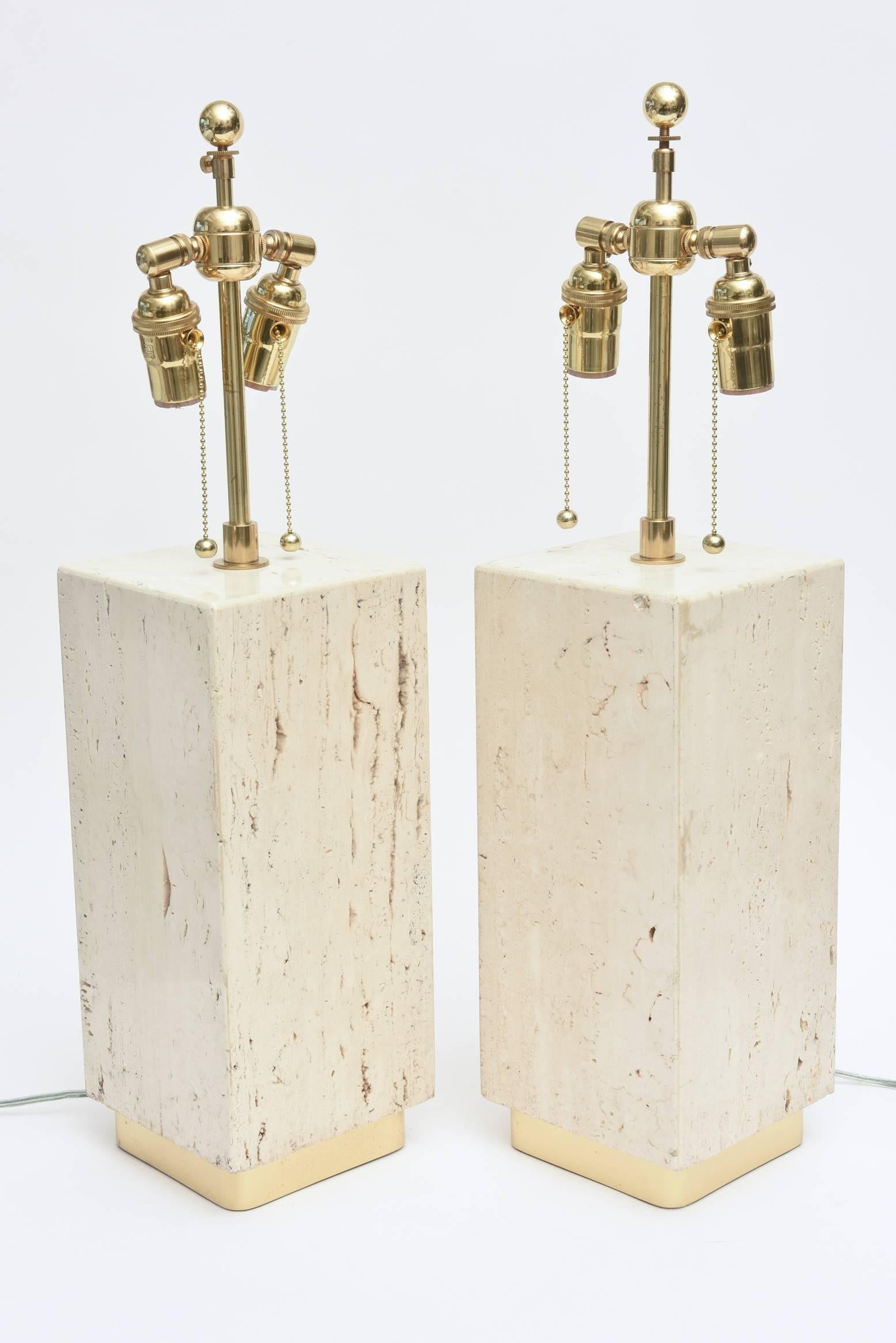 These timeless lamps of travertine and brass are organic in materials and modern in form.
The polished brass square bases and the polished brass hardware add to the yin and yang of earthy meets polish.
Their thick column form adds modernity.
 The
