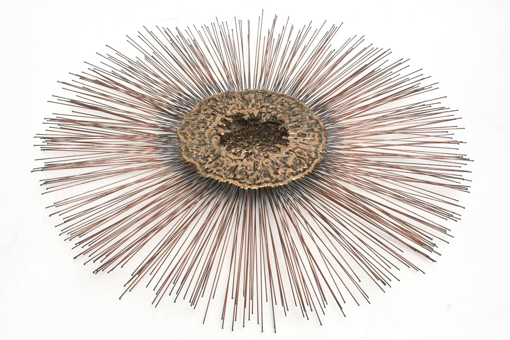 This mid size in the Jere manner of a starburst wall sculpture has copper rods/spokes and a molten brass center double interior. The interior portion looks jewelry formed.
  