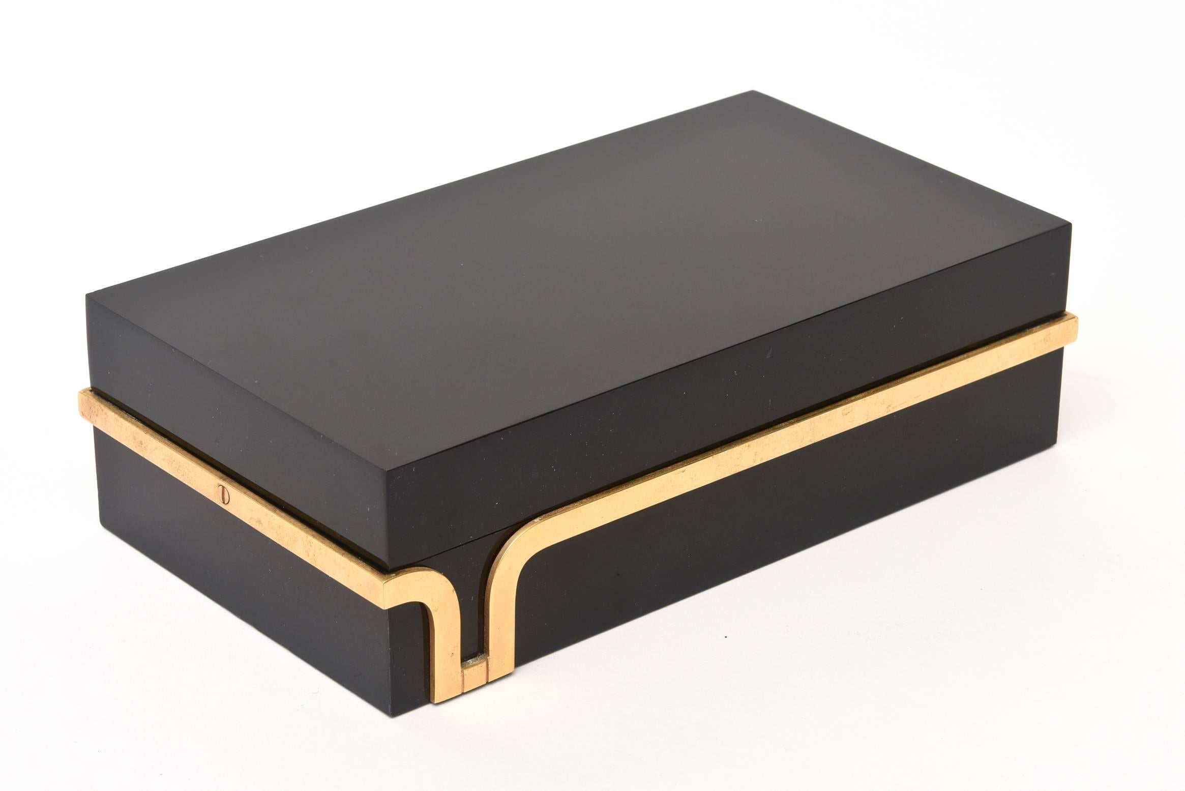 This stunning black lucite and sculptural brass detail of this two-part lidded box is a great accessory for any cocktail table and or desk. The top is not hinged but lifts off as shown in the photos. The architectural design of the brass trim is