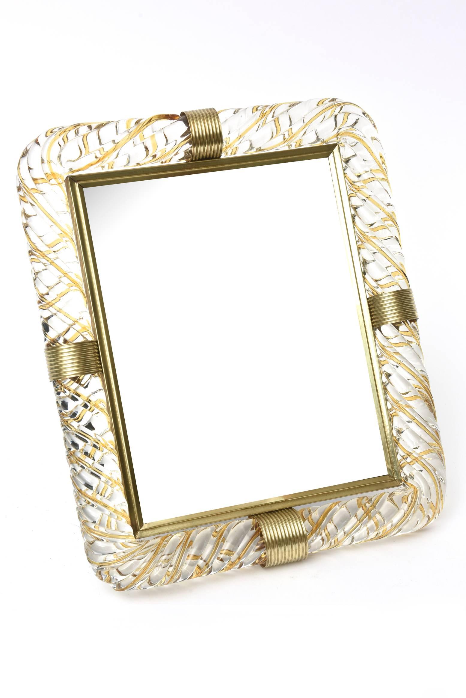 This gorgeous and heavy Italian vintage Murano glass and brass picture frame is the work of Barovier e Toso. The four brass thick rings have been polished. It has amber glass rolled into the clear glass. The latticino technique and the rolled