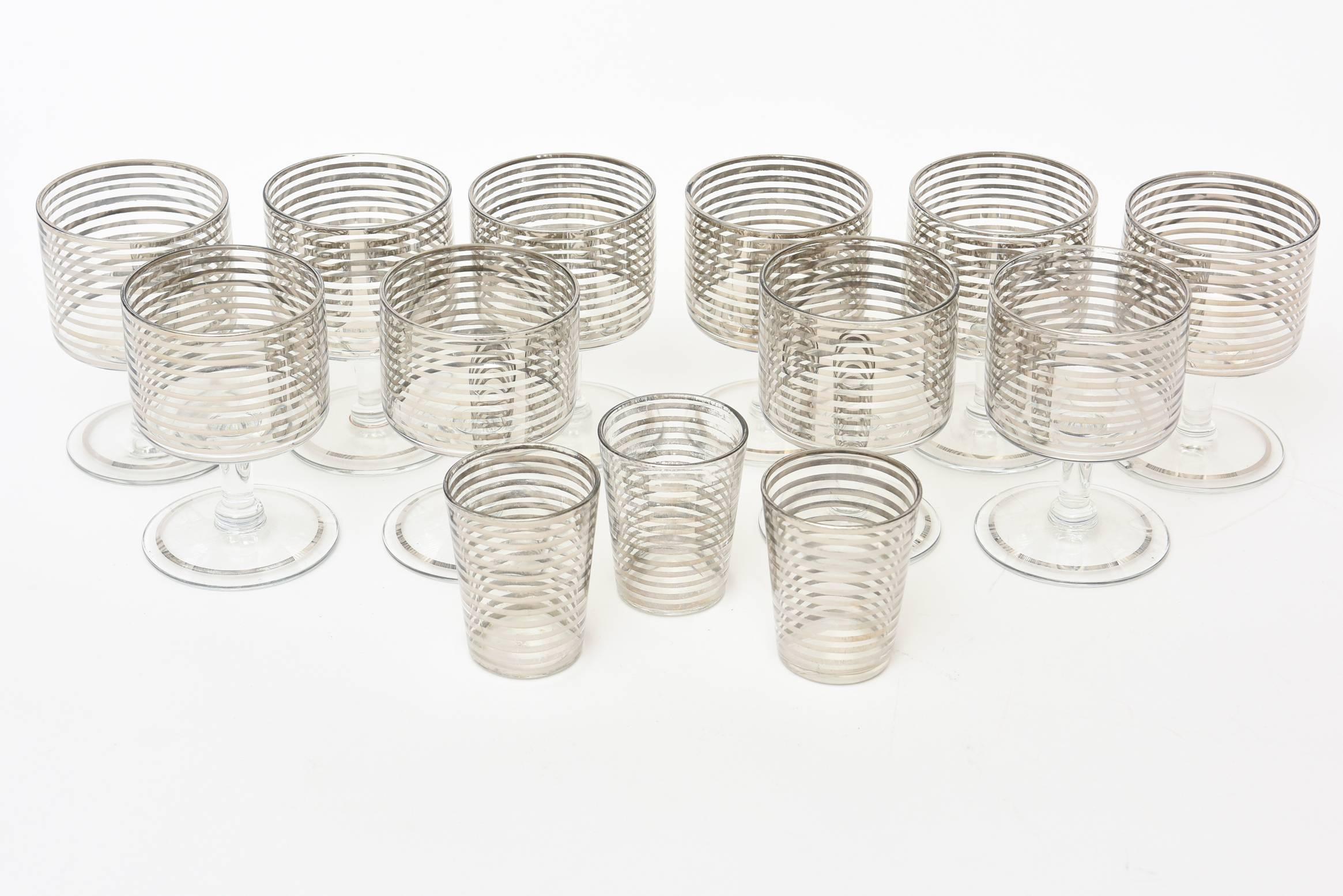 This set of barware is from the 1940s and is silver lined glass. It consists of 10 small cordials with a round glass base with silver line and 3 shot glasses. The concentric silver lines forms a geometric circle. It has an art deco style. The 3 shot