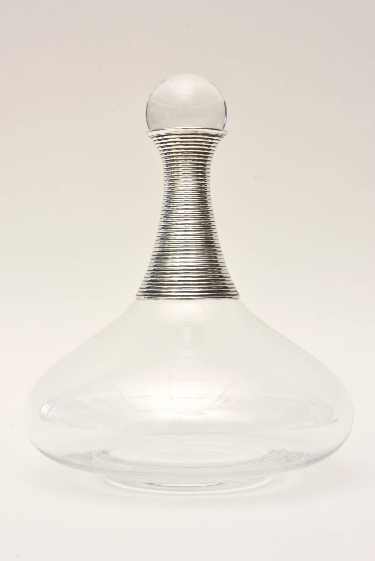 This amazing sexy bulbous glass decanter with a glass stopper has ribbed silver plate neck and a glass ball stopper. The shape is beautiful. It is from the 1960s and from a company in Canada that is the equivalent of what Tiffany is in America. It
