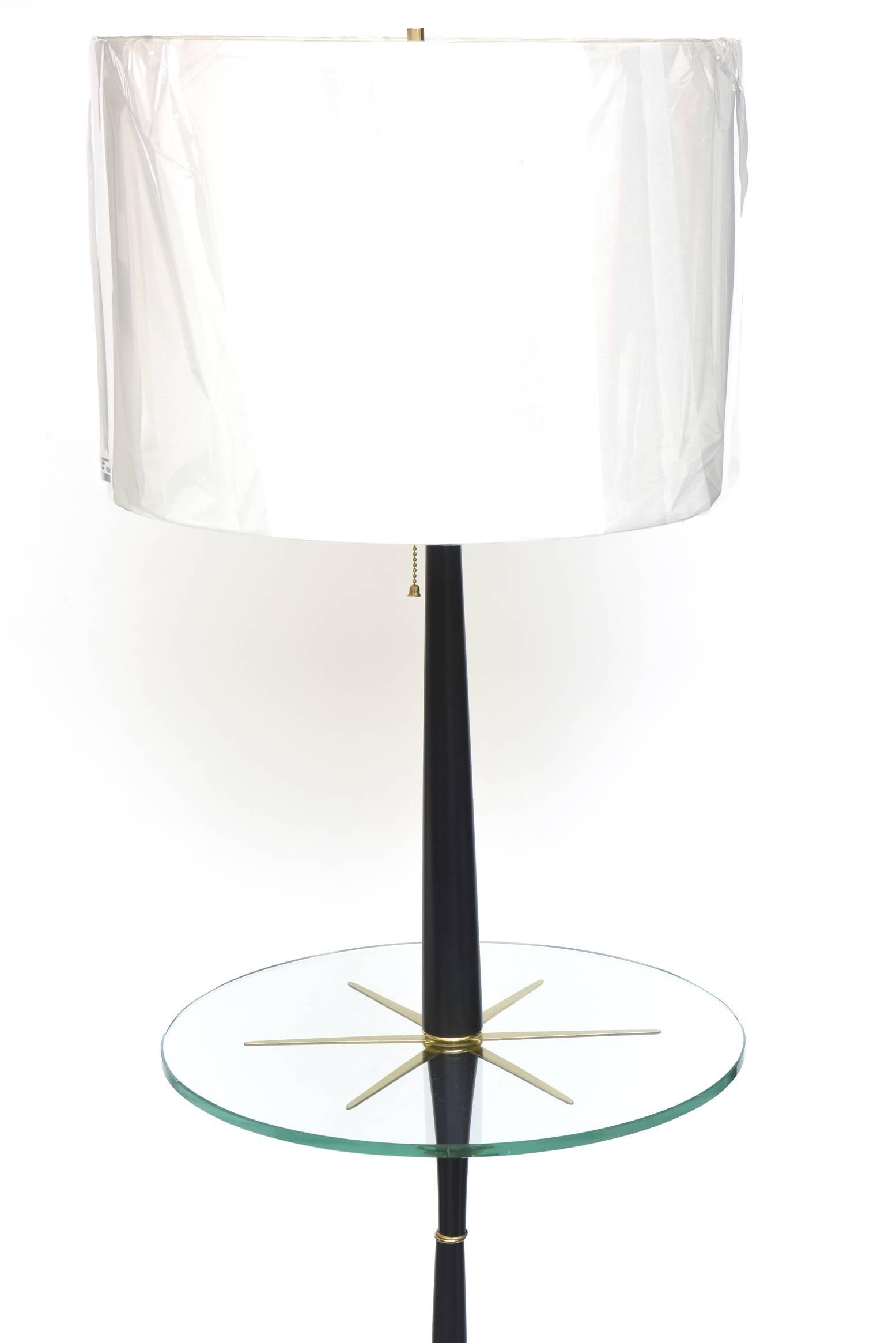 This wonderful wood and brass Mid-Century Modern lamp table and or floor lamp is the design of Tommi Parzinger and has been fully restored. All the brass details have been professionally polished and the wood has been ebonized with a satin finish.