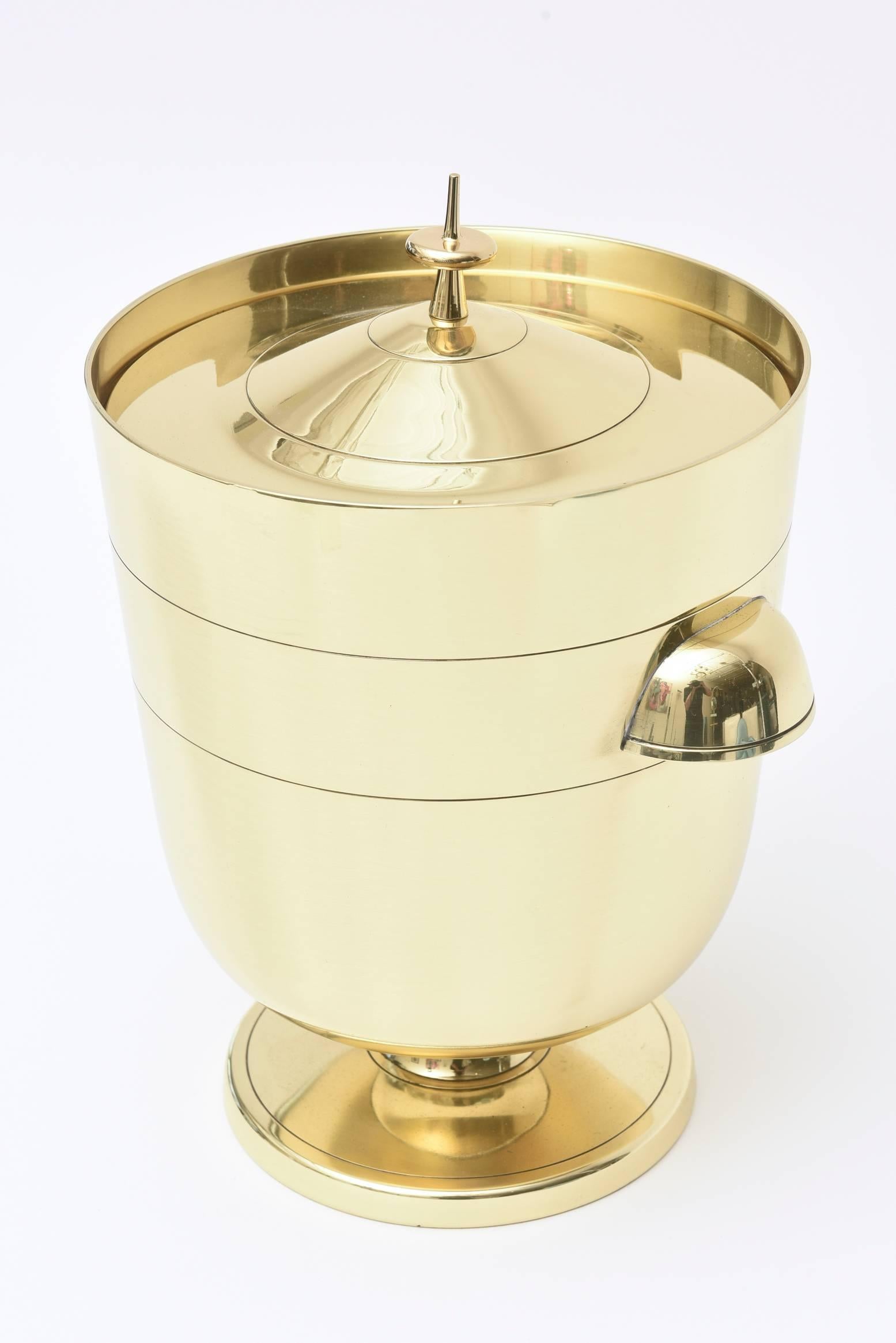 This Classic modernist Mid-Century Modern and solid brass hallmarked Tommi Parzinger for Dorlyn ice bucket and or champagne cooler is always timeless with its form and lines. It has the original mercury silver glass liner. This is great barware and