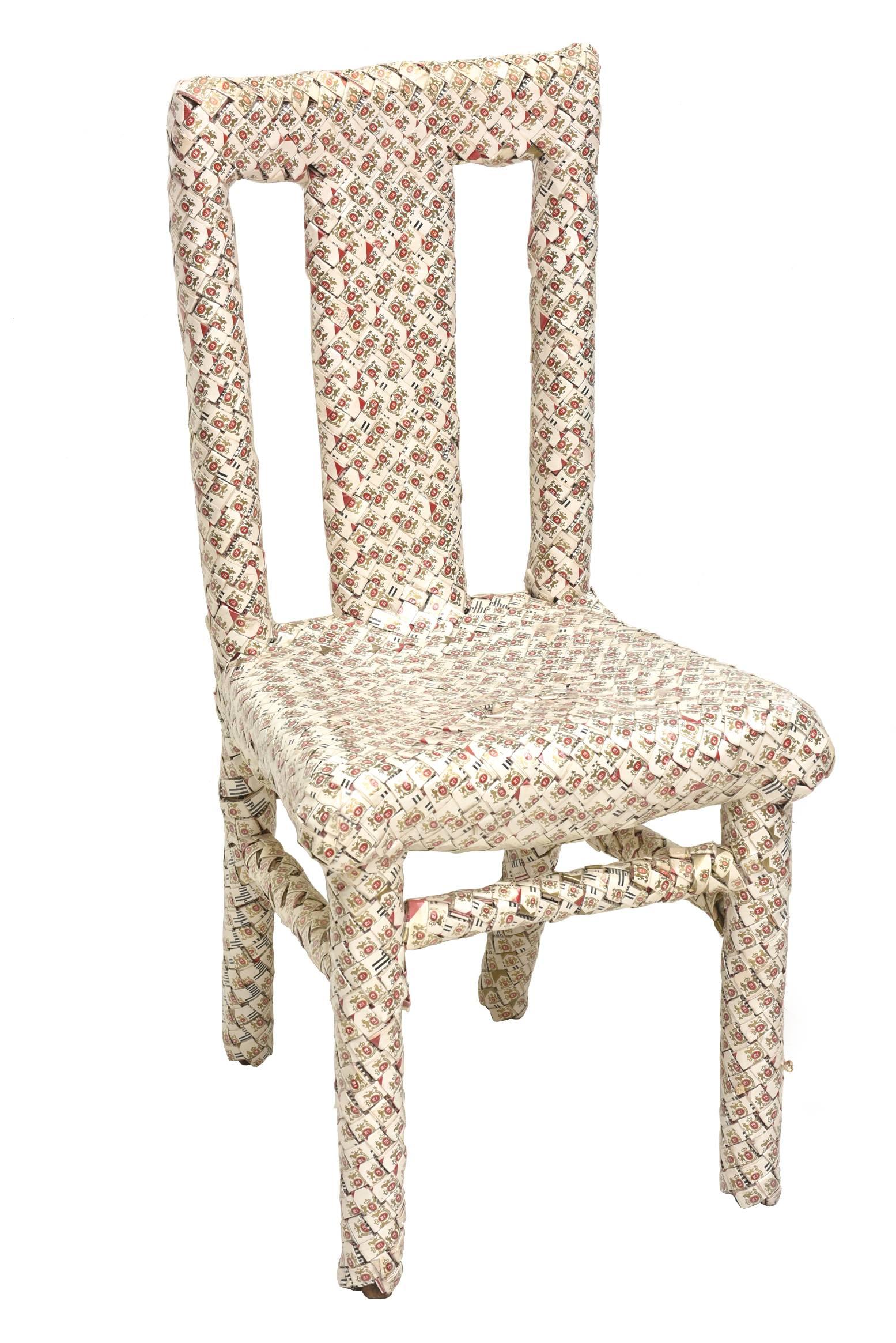 This amazing chair that is a work of art executed with over 1,000 boxes of Marlboro cigarette boxes is from the genre of prison art meets Folk Art. The boxes were folded and weaved and took years of time to make. This is all done over wood. It is by