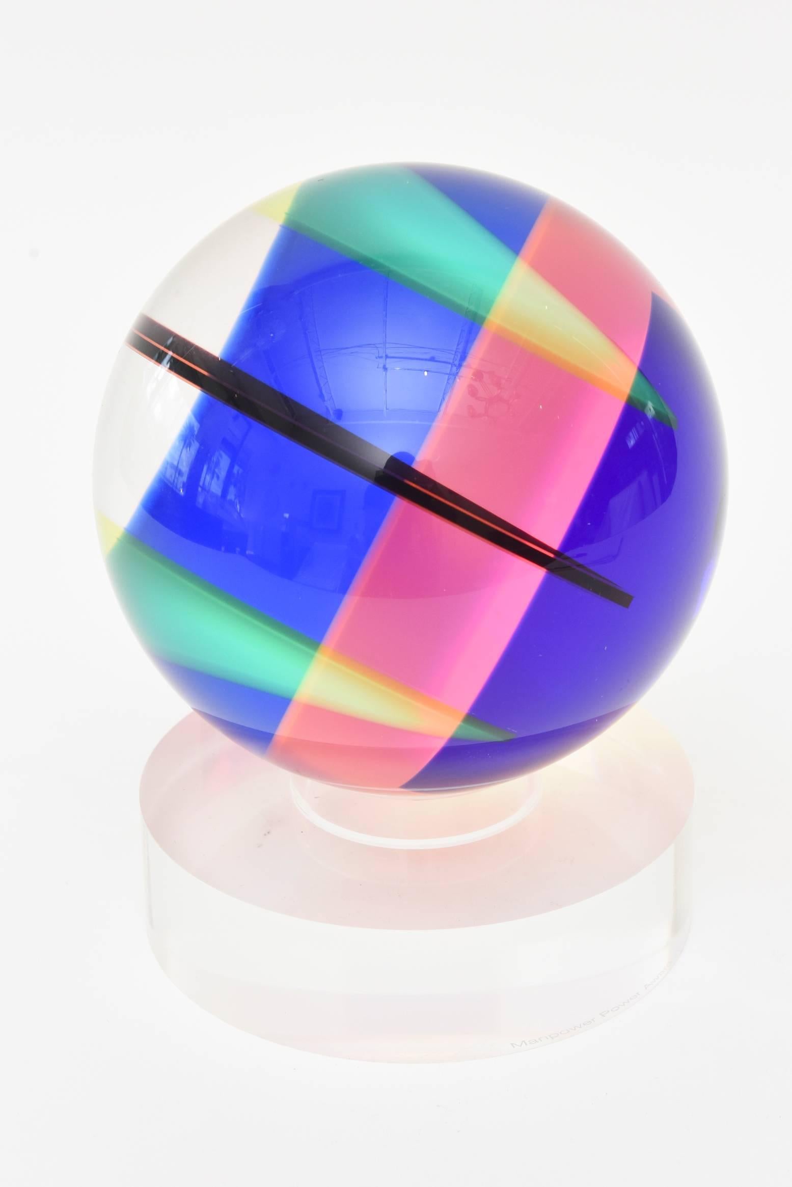 This fabulous signed Vasa Mihich laminated Lucite sphere ball abstract sculpture is dated 2006. It has intersecting planes of colored Lucite that change with the play of light and turn. Each way there are different planes of color and abstractions.