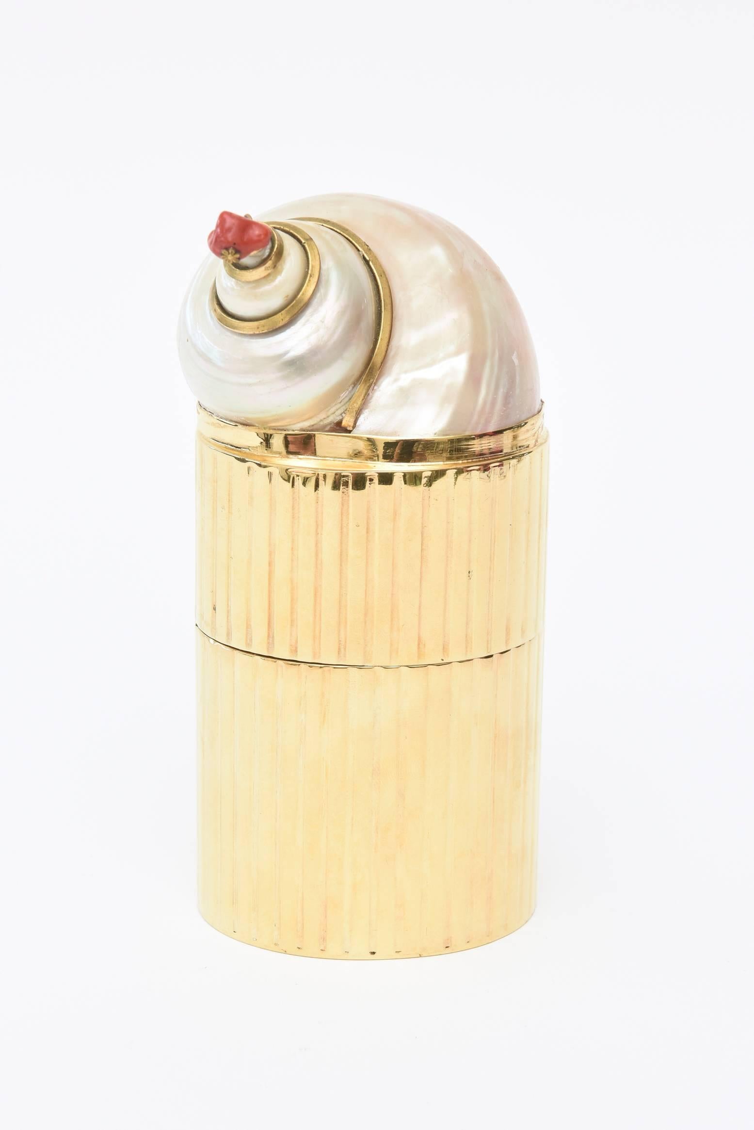 This stunning two-part real gold plated vintage box has a beautiful chamber swirled nautilus shell with surround gold band. The tip has a real piece of dangle coral attached. It is organic modern.
It is from the 1970s and was originally sold at