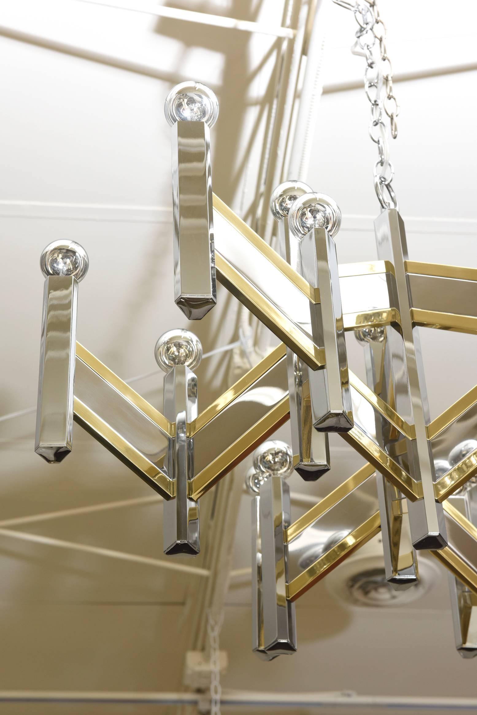 This mixed metals of brass and nickel silver of this vintage Italian Gaetano Sciolari for Lightolier chandelier has been professionally polished and rewired. The dramatic zig zag chevron pattern alternating nickel silver and brass houses 15-light