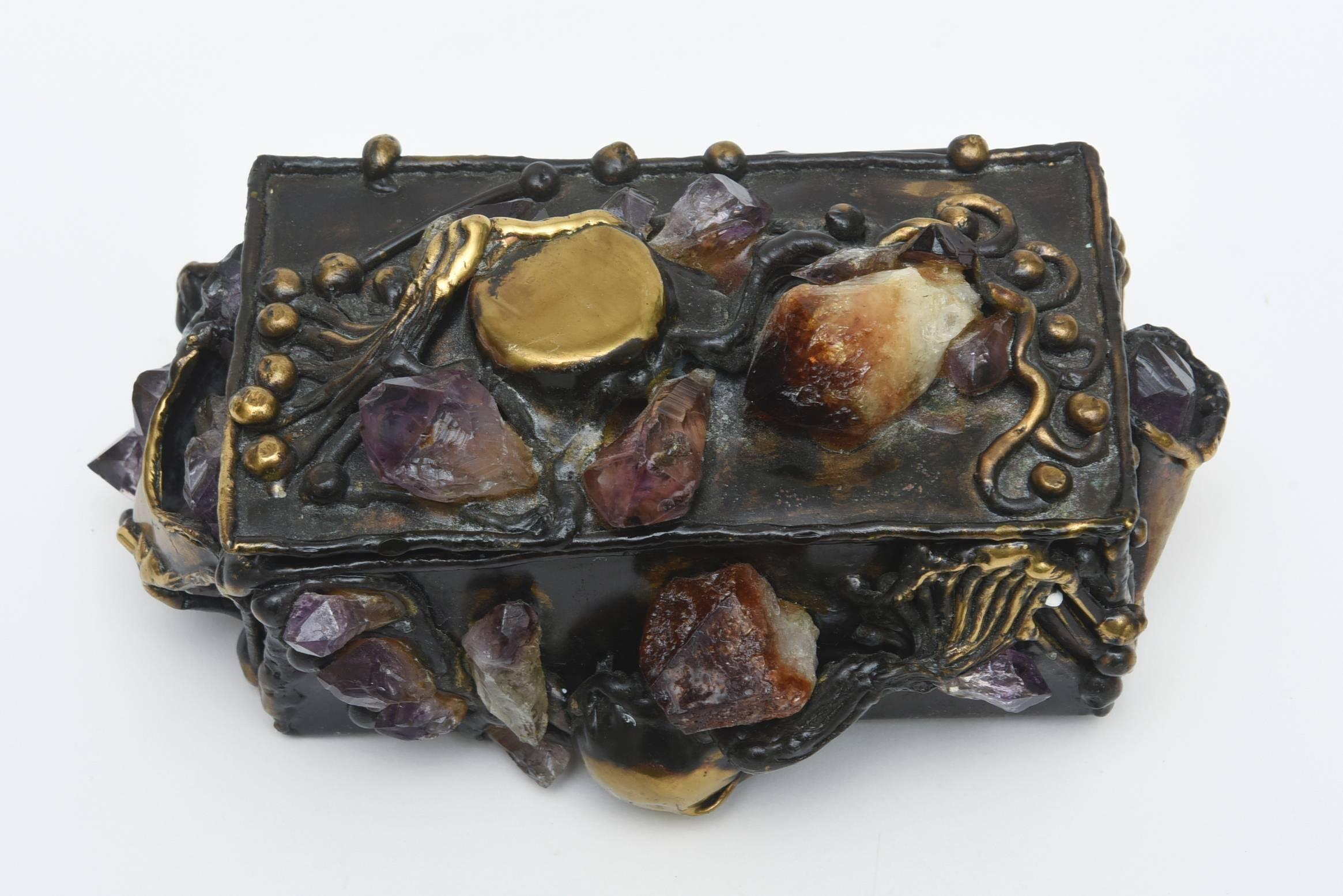 This is art, sculpture and a jewel.... all in one small box.
It is Brutalist in form, beautiful in stones of amethyst and quartz and mixed metals of copper and brass.There are jettings of stones and brass implements protruding... in sculptural form.