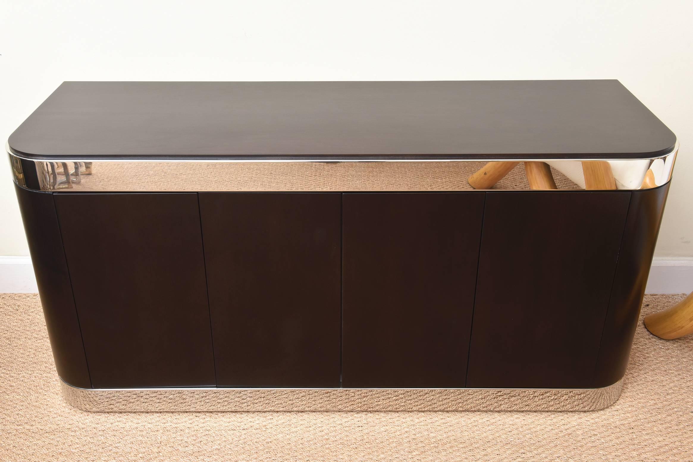 The radius corners of this fabulous Leon Rosen for Pace cabinet has handsome appointments and lines to it. The mahogany wood has been ebonized and the stainless steel banding has been polished professionally. All of the interior also has been