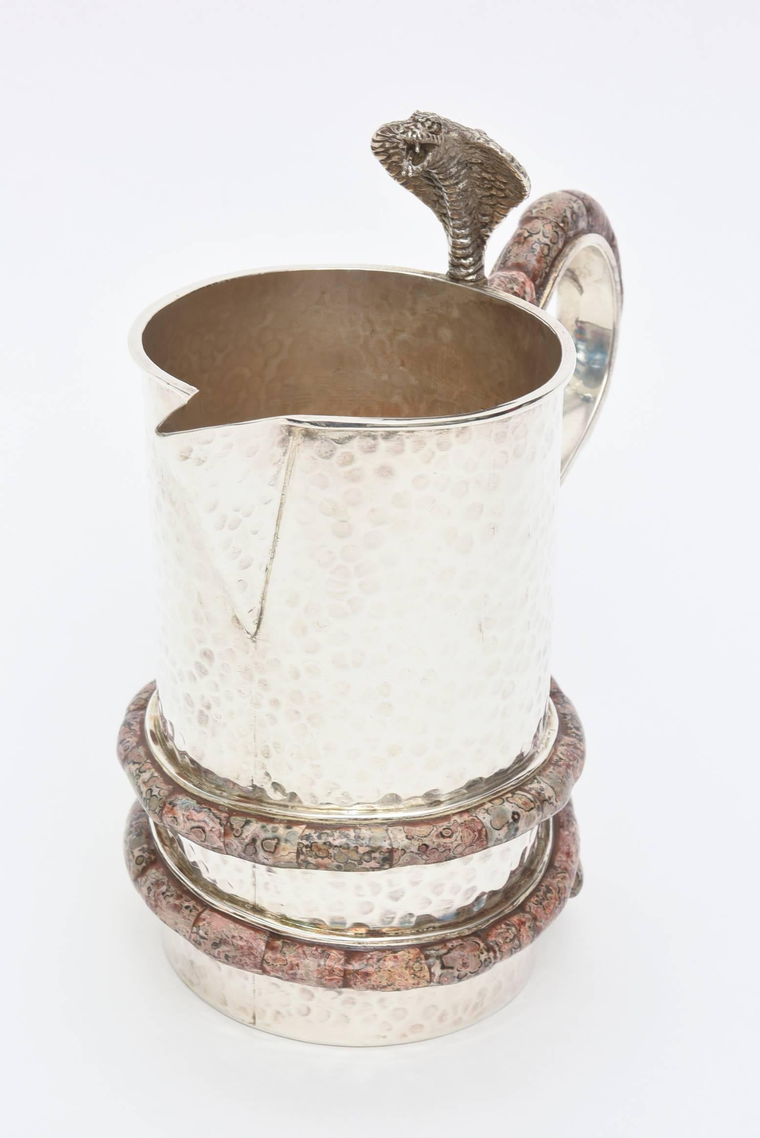 This sculptural and enticing hand-hammered silver plate pitcher/vessel is by one of the masters in Mexico.
It is not signed but is her work.
The exotic serpent that wraps and cascades the pitcher is so well executed and has beautiful details. The