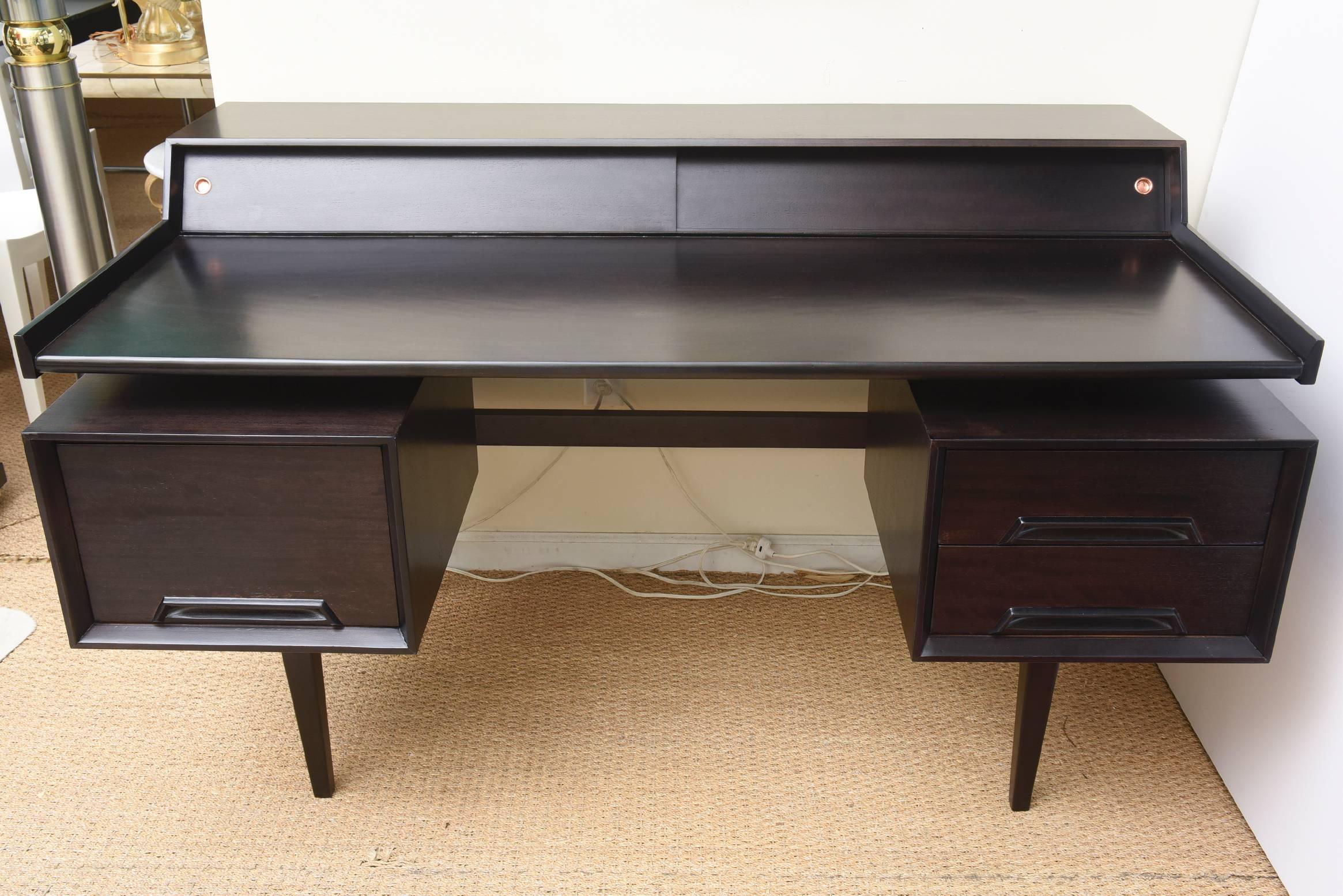 This fantastic Milo Baughman sculptural desk has been newly ebonized over mahogany. The top portion of the floating desk opens to little compartments for mail, desk accessories, envelopes with two original polished copper tabs.
This has great