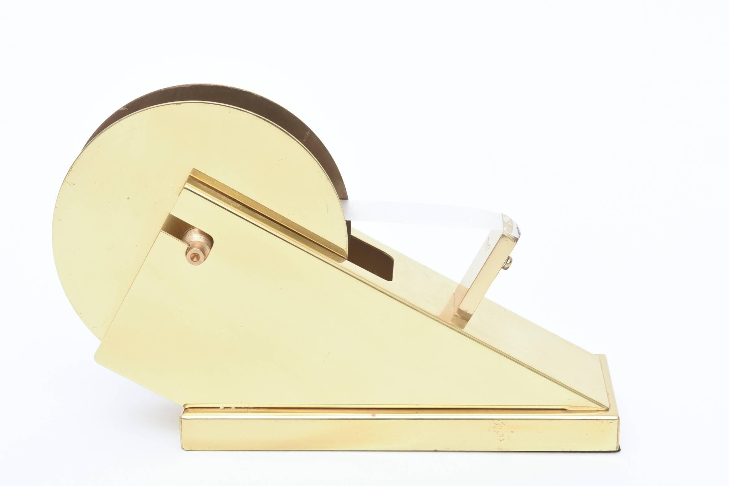 Machine Age meets modern in this vintage sleek and sculptural large brass tape dispenser and holder. It is great from all angles and a wonderful desk accessory! It even holds different widths of tape and unbolts to do so. It is from the 1970s. This