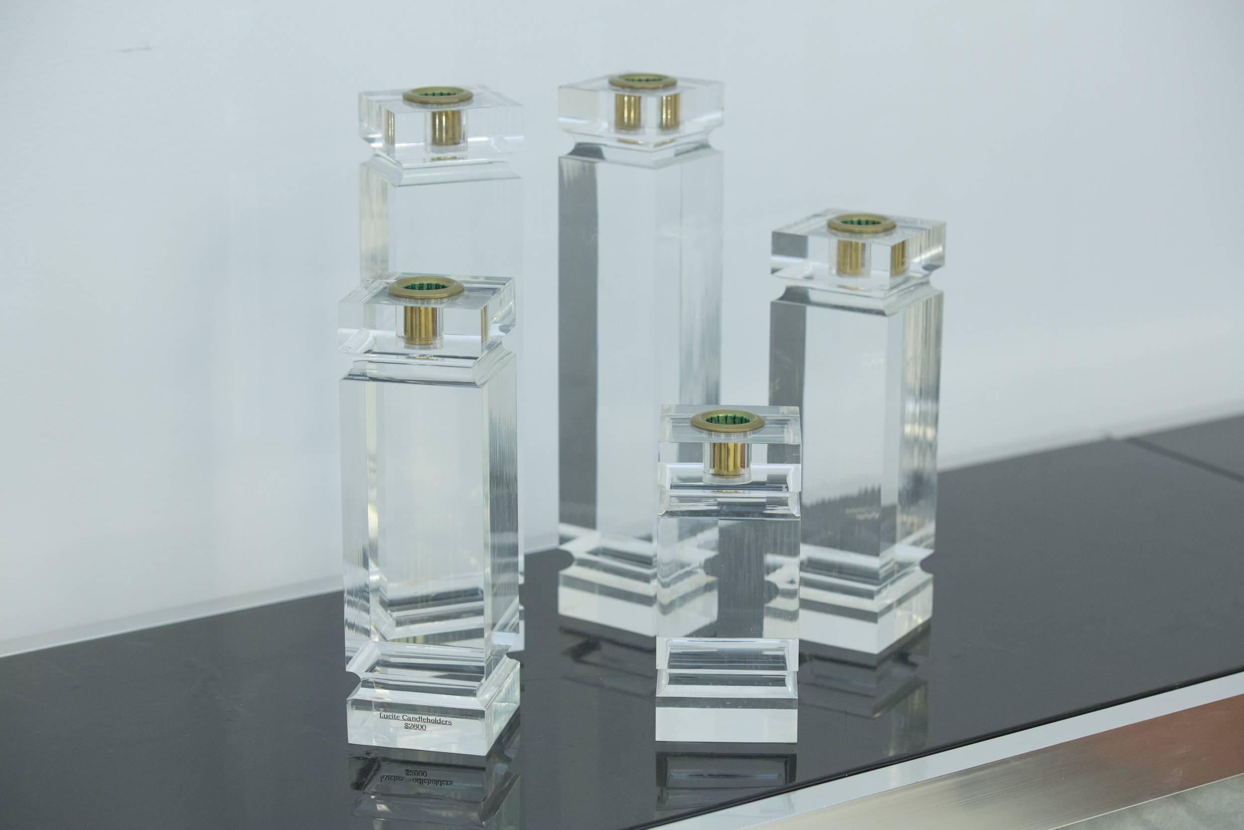 Set of five square solid Lucite candleholders 
with brass inserts.
Measures: 3" SQ x 12.5" H or 9.5" H and 6.5" H.