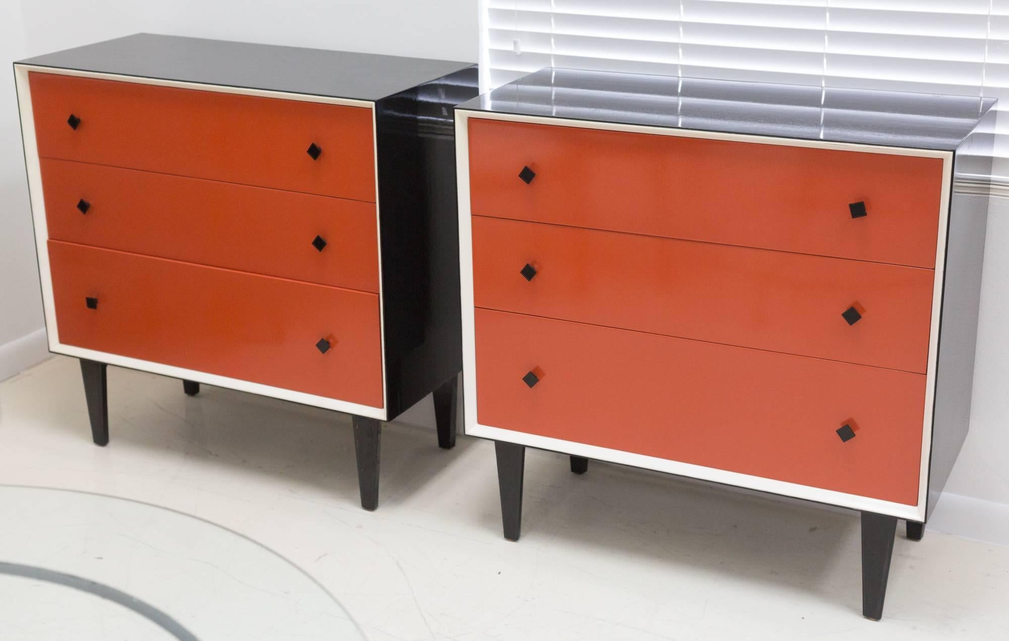 Pair of three-drawer dressers in Maison Jansen style
with orange fronts outlined in white trim.
Recently lacquered case and solid wood,
tapered legs in black piano finish, 
original square pulls.
  