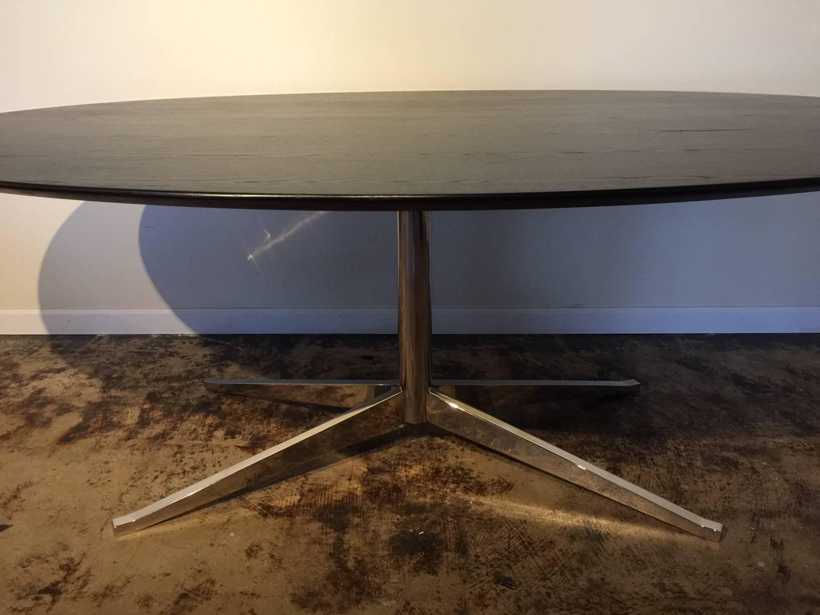 Florence Knoll elliptical dining or conference table; Designed in 1961
on metal pedestal base splaying to four feet; The underside of the top has a deep knife-edge bevel creating a slender profile. Like all of Florence Knoll's designs, it is