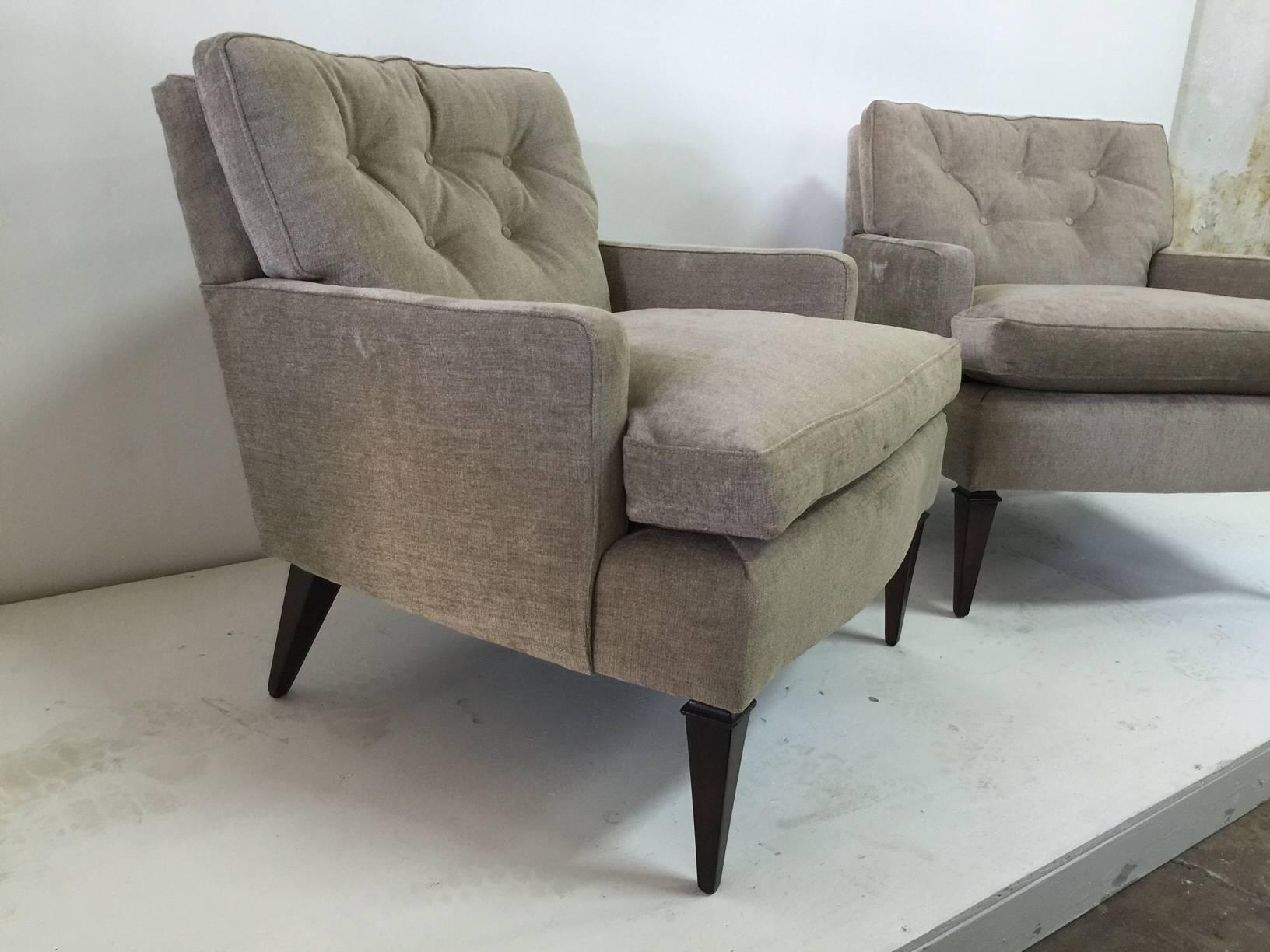 These are a lovely pair of linear and great scale armchairs with beautiful tapering legs lacquered in ebonized finish. Upholstered in taupe finish velvet fabric. These are low chairs but very comfortable.