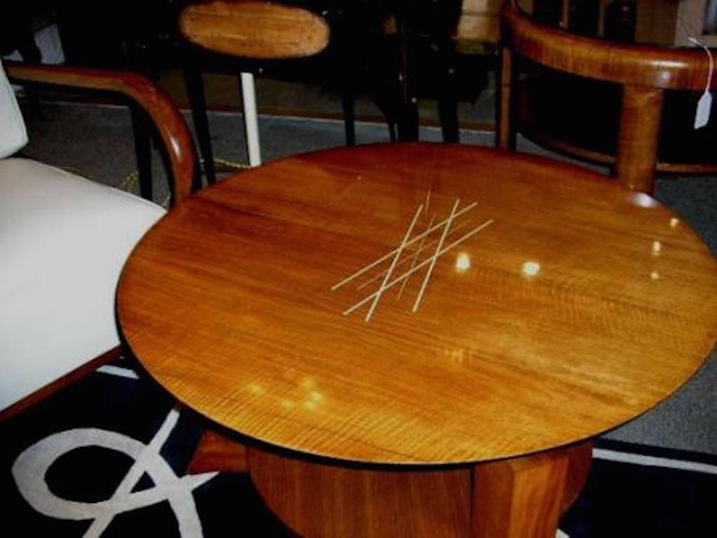 A round Art Deco coffee or cocktail table in mahogany featuring double tiers, three squared legs that terminate in curving feet and large faux ivory ball shaped top supports. The table also features a top that is inlaid with several faux ivory lines