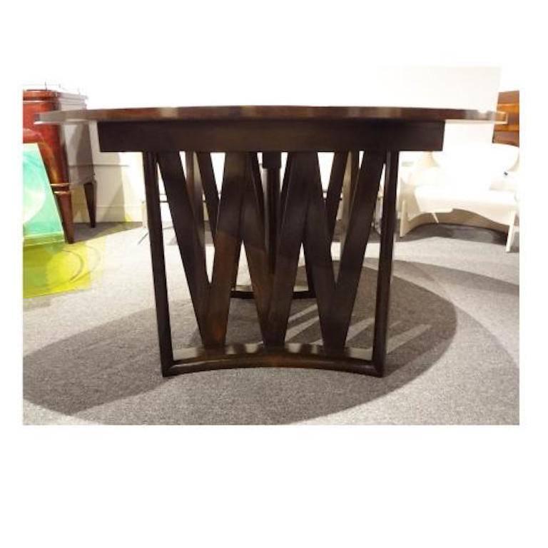 A round expanding Mid-Century dining table featuring a body in mahogany with a two-piece base composed of rounded supports with zig zag decorations. The tabletop has been fully restored. Two leaves extend table to L. Measures: 82.75