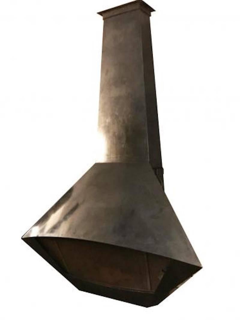 Mid-Century Modernist fireplace featuring a futuristically shaped body in patinated steel with a tapering chimney, ceiling mount, curved top fire box and removable screen with two handles. In the style of Jean Royère, France, circa 1960.
