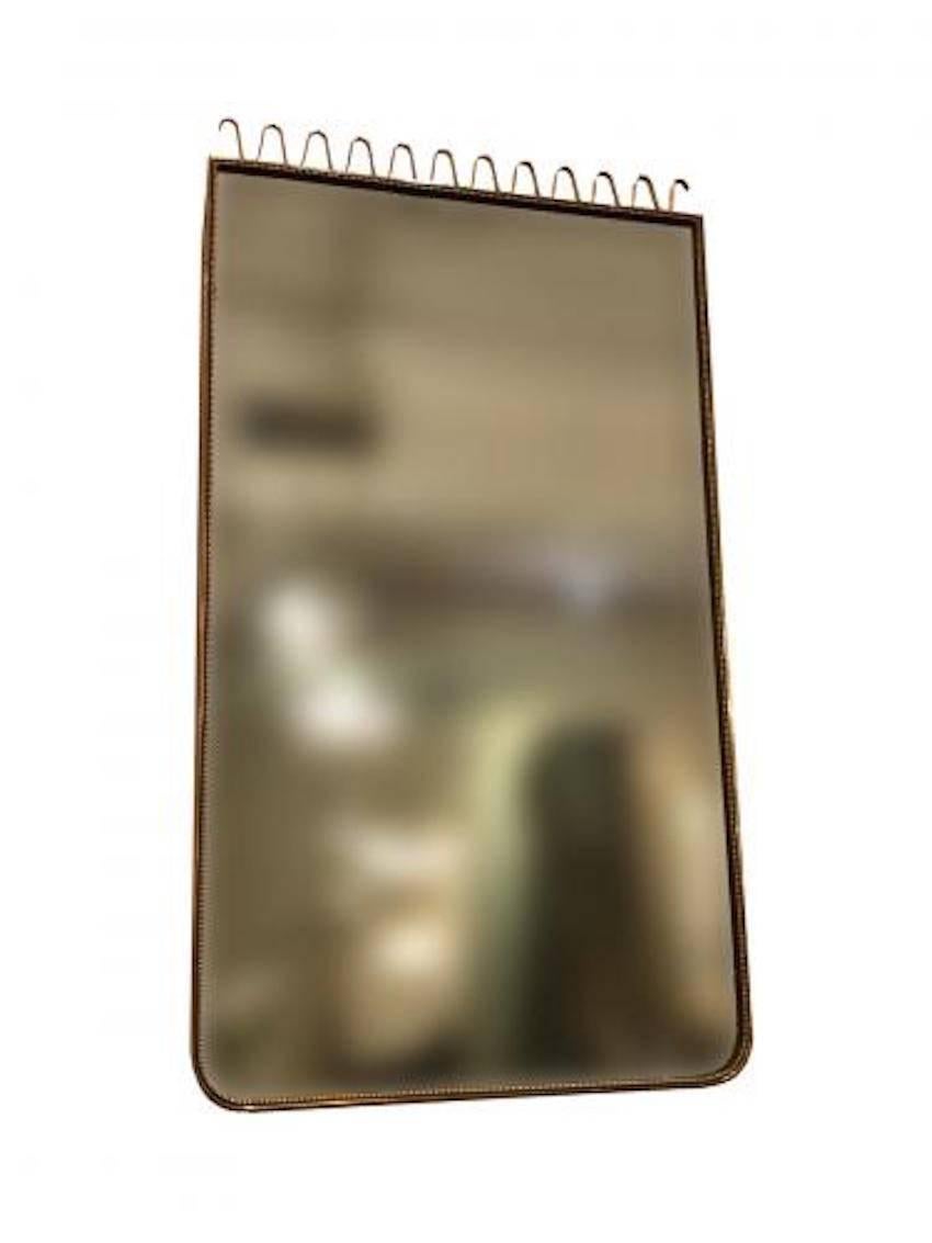 Gio Ponti Attribution. Rectangular midcentury wall mirror featuring a frame with a square top and rounded bottom corners all in brass with a squiggle top crown detail and beading on the inner edge of the frame. Italy, circa 1950.