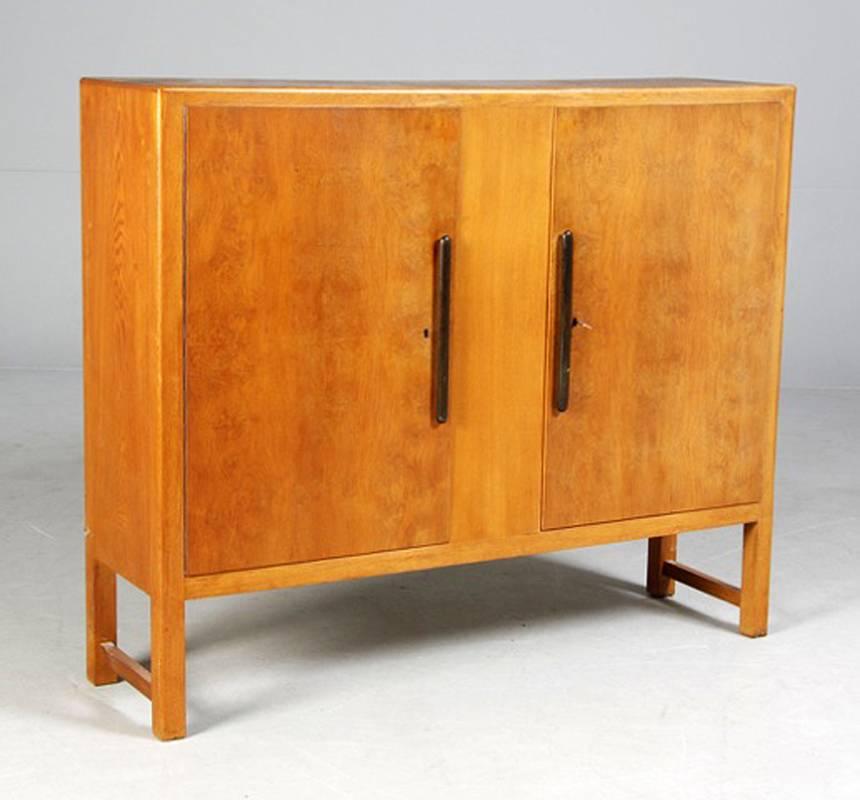 Danish 1940s-1950s cabinet with figured oak doors and black lacquered handles. The cabinet opening to two compartments on each side opening to two shelves (see third photo detail).