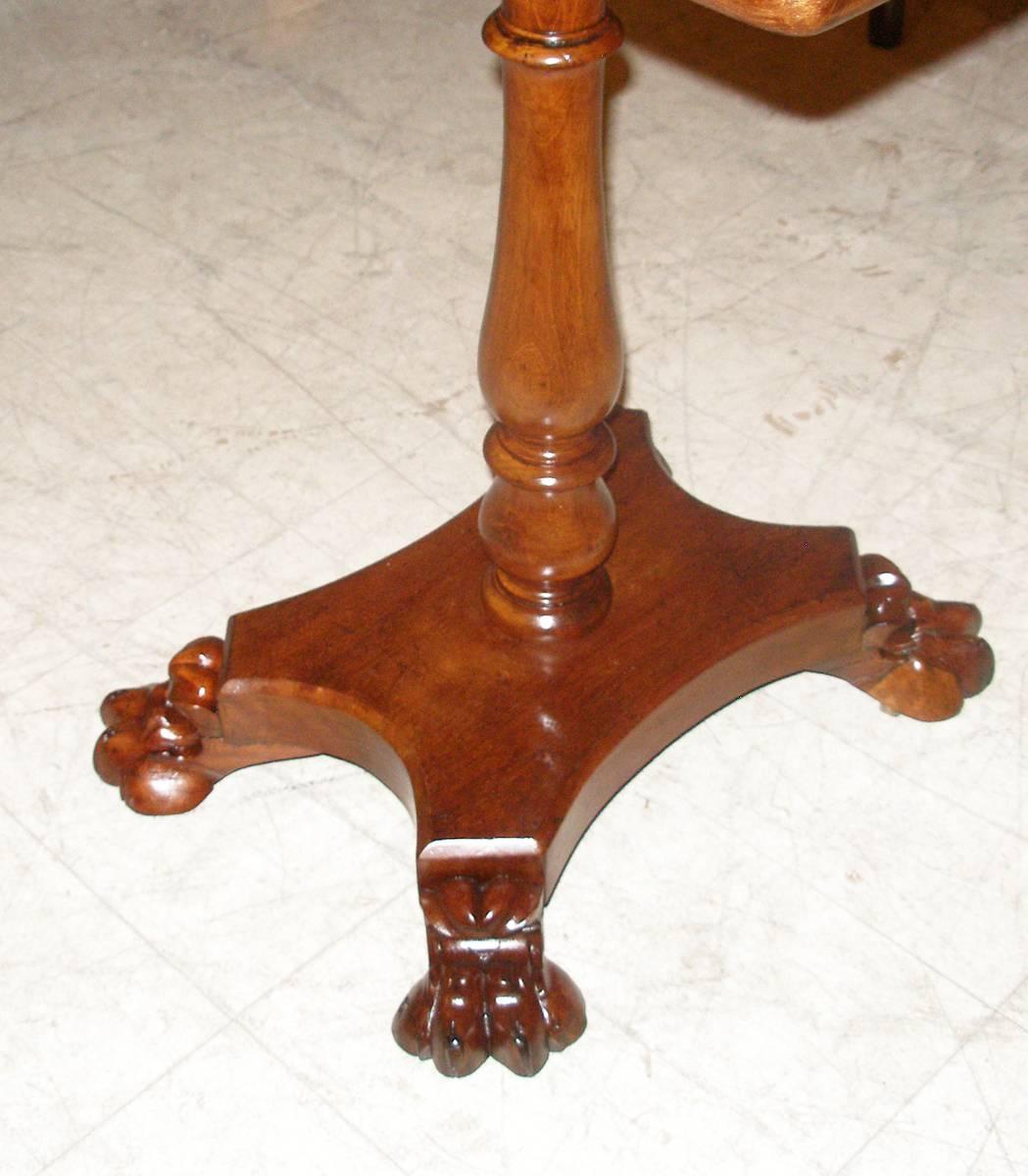 Neoclassical side or lamp table of well figured mahogany, circa 1820s-1830s. The top on a turned balustrade column on a incurved quadpartite base ending in carved paw feet.