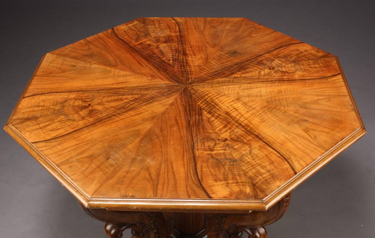Danish 19th century walnut octagonal neoclassical center table, circa 1870s-1880s. The quarter veneered octagonal top over a plain moulded frieze supported by four S-scroll dolphin supports with acanthus and palmetto carvings surrounding a fluted