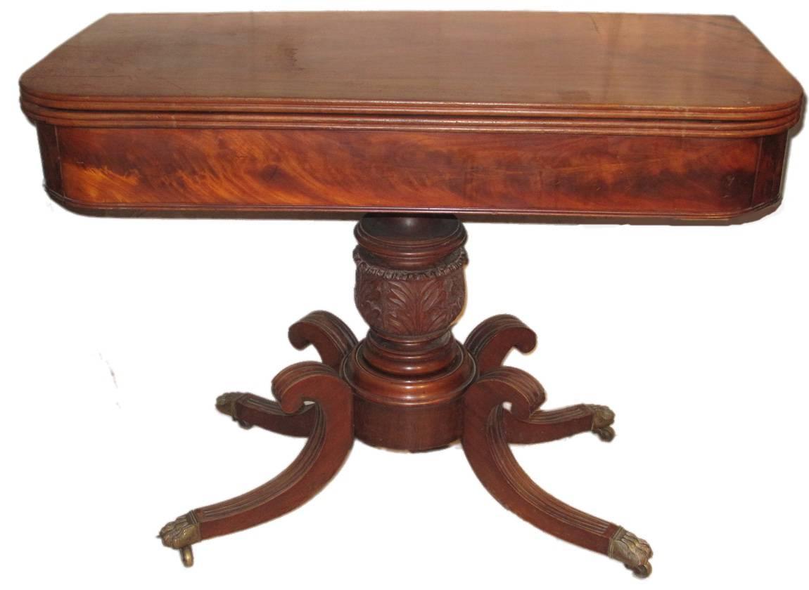 Pair of American classical flame mahogany card tables, circa 1820-1830. The tops with molded edges over a plain frieze of flame mahogany. The tops opening to flame mahogany surfaces and supported by turned pedestals with central acanthus leaf