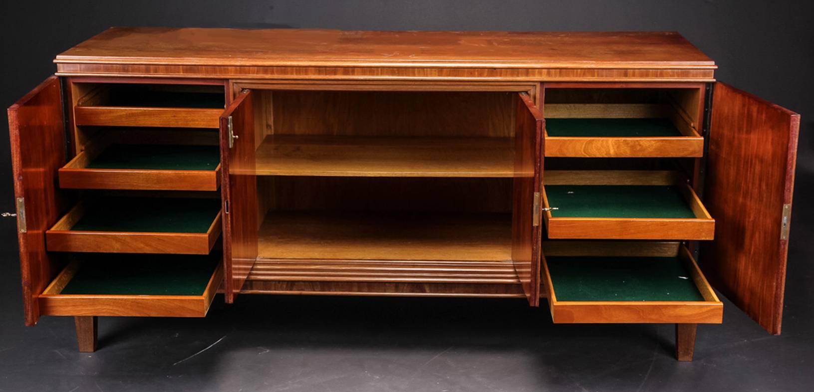 Danish figured mahogany Mid-Century sideboard. The interior fitted with four baize-lined pull-out drawers on each side with the center doors opening to an interior space fitted with shelves.