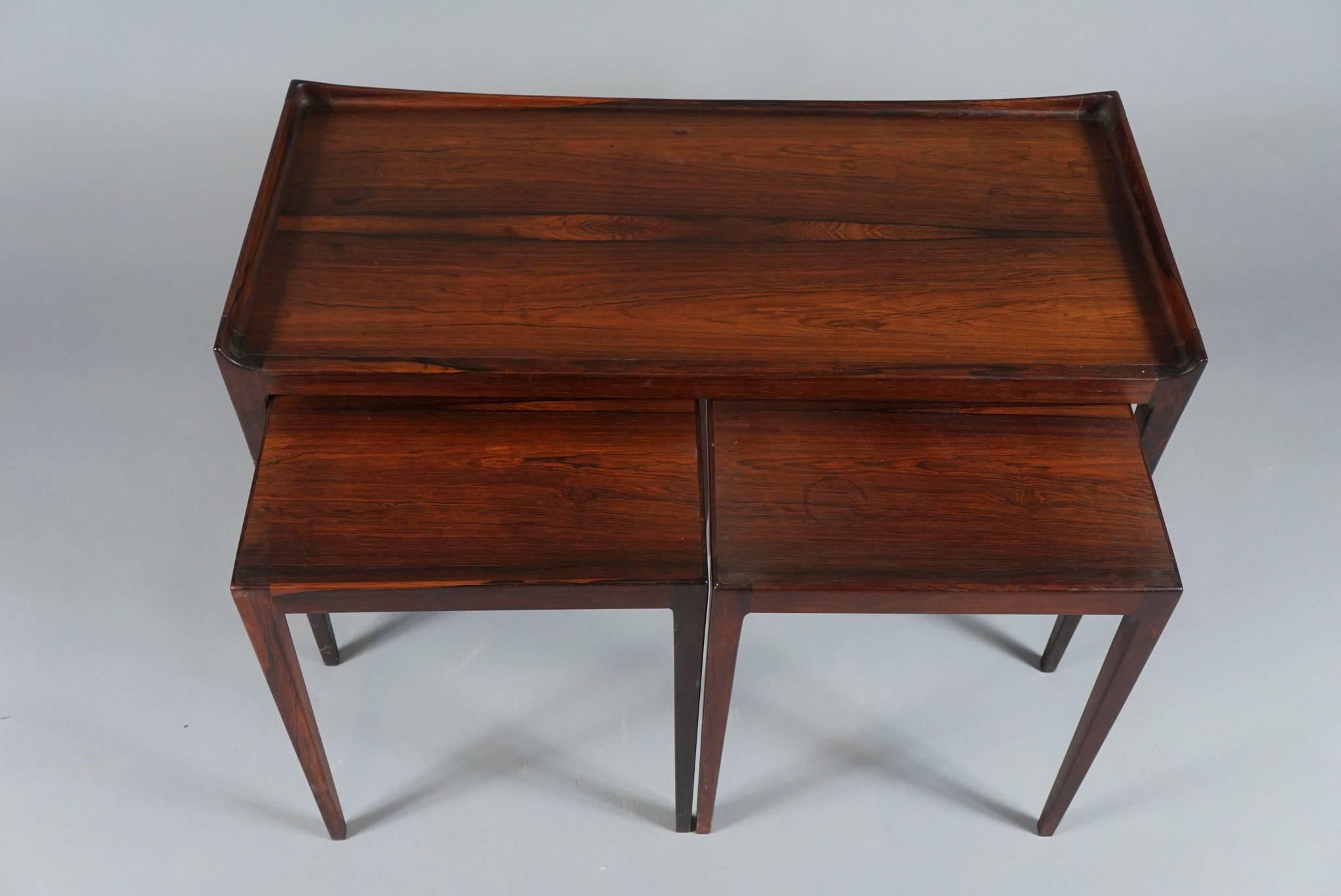 Finely crafted set of three tables having tapered legs by Danish designer, Kurt Ostervig in solid rosewood, the two square tables fitting underneath. The smaller tables measure: 14