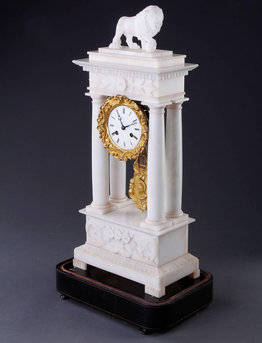French Napoleon III marble and ormolu style mantel clock with glass dome. The marble stand mounted with a lion and ball figure on a tiered and dentil moldings above a floral carved frieze supported by four columns on a similarly carved base resting