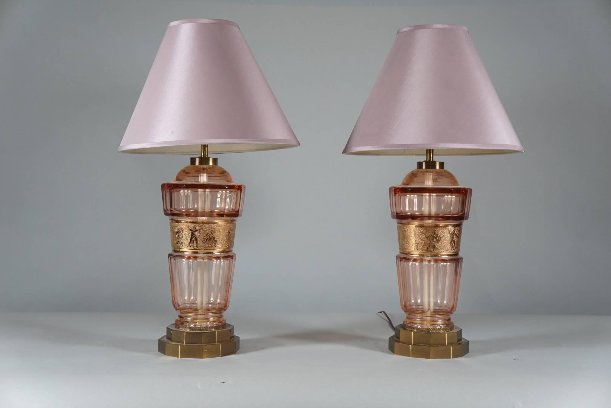 A pair of fine quality Art Deco decagonal glass lamps, the glass in light pink tones, the glass with a centrally placed gilded frieze with images of classical warriors. The lamps mounted on brass bases. The lamps by Czechoslovakian luxury glass