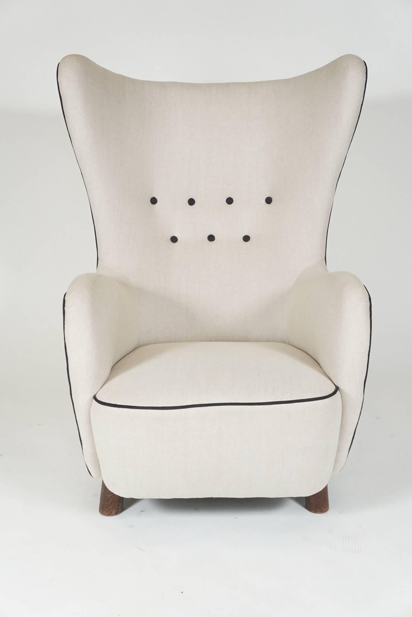 Wingback lounge chair by Mogens Lassen from Denmark, 1930s covered in white linen with black piping and buttoning.