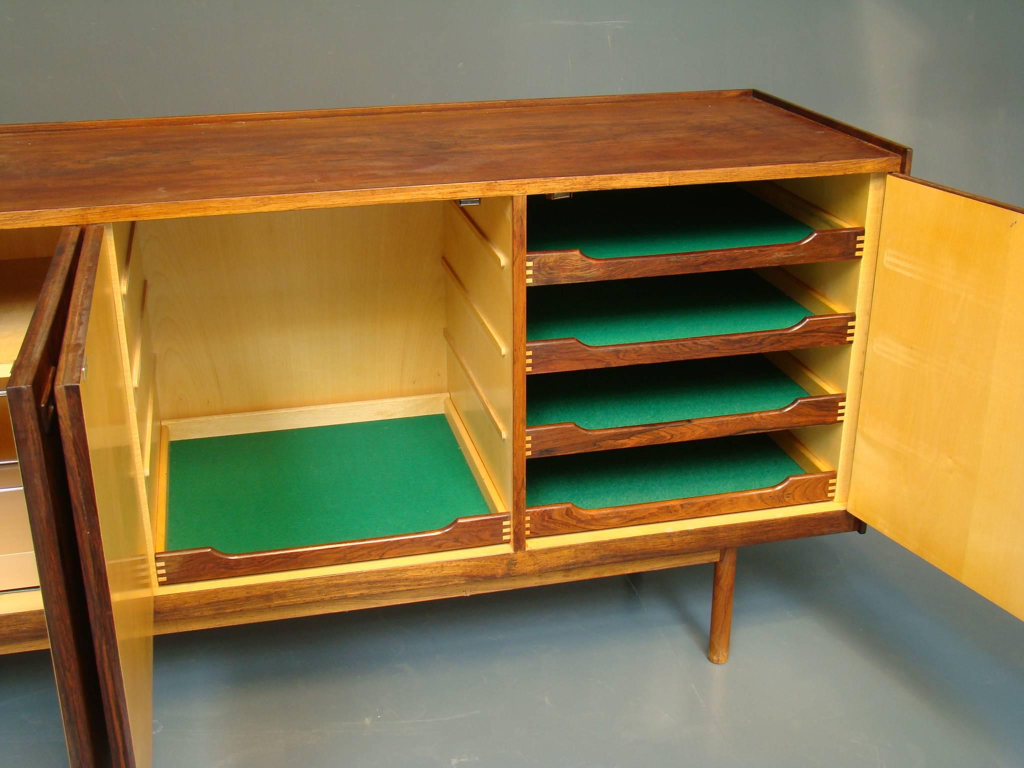 Danish modern sideboard by well-known furniture designer Ib Kofod-Larsen, long and narrow, with excellent storage in finely figured rosewood.  The combination lock feature does not work but the cupboard can be opened.  