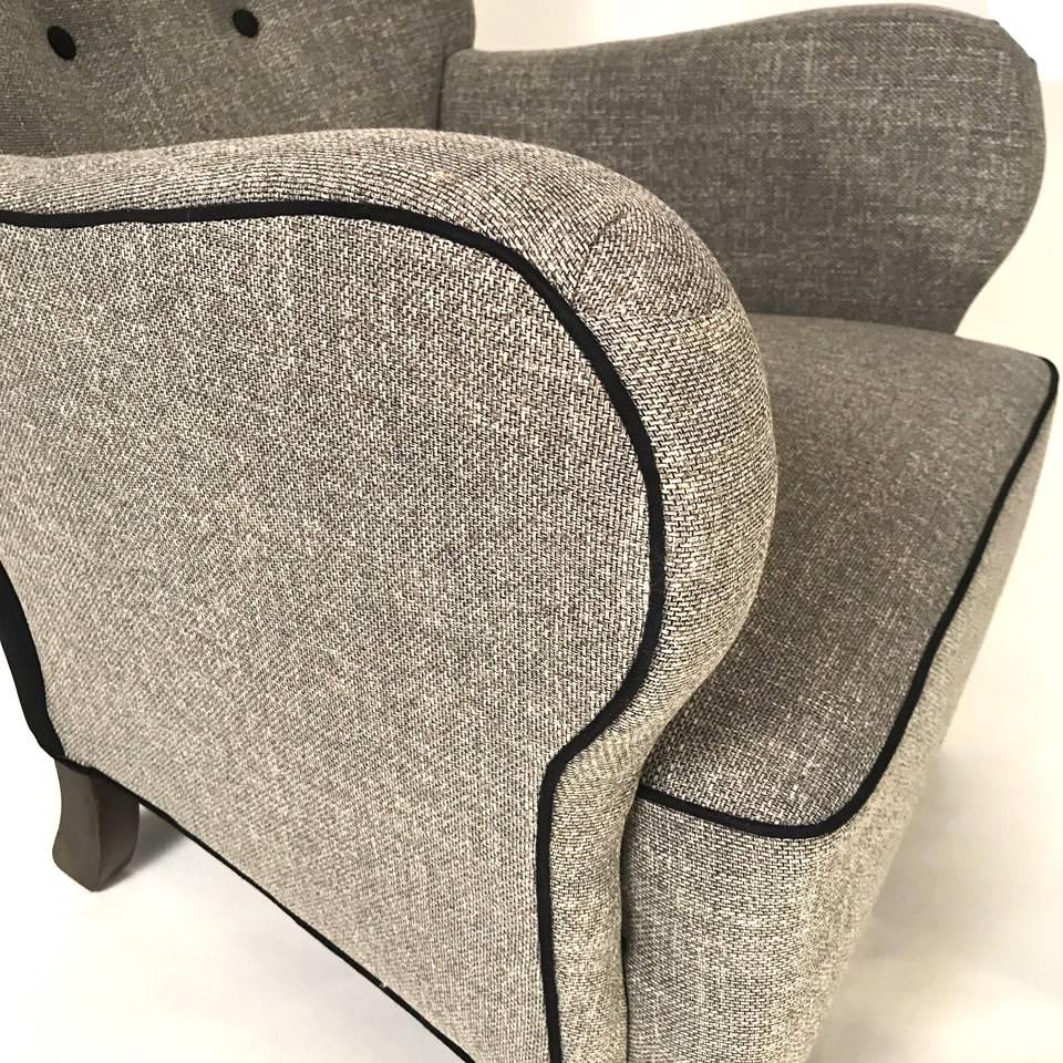 Pair of Danish 1940s of architectural form. The armchairs newly upholstered in a grey linen fabric with black piping. The armchairs supported by stained beech legs.