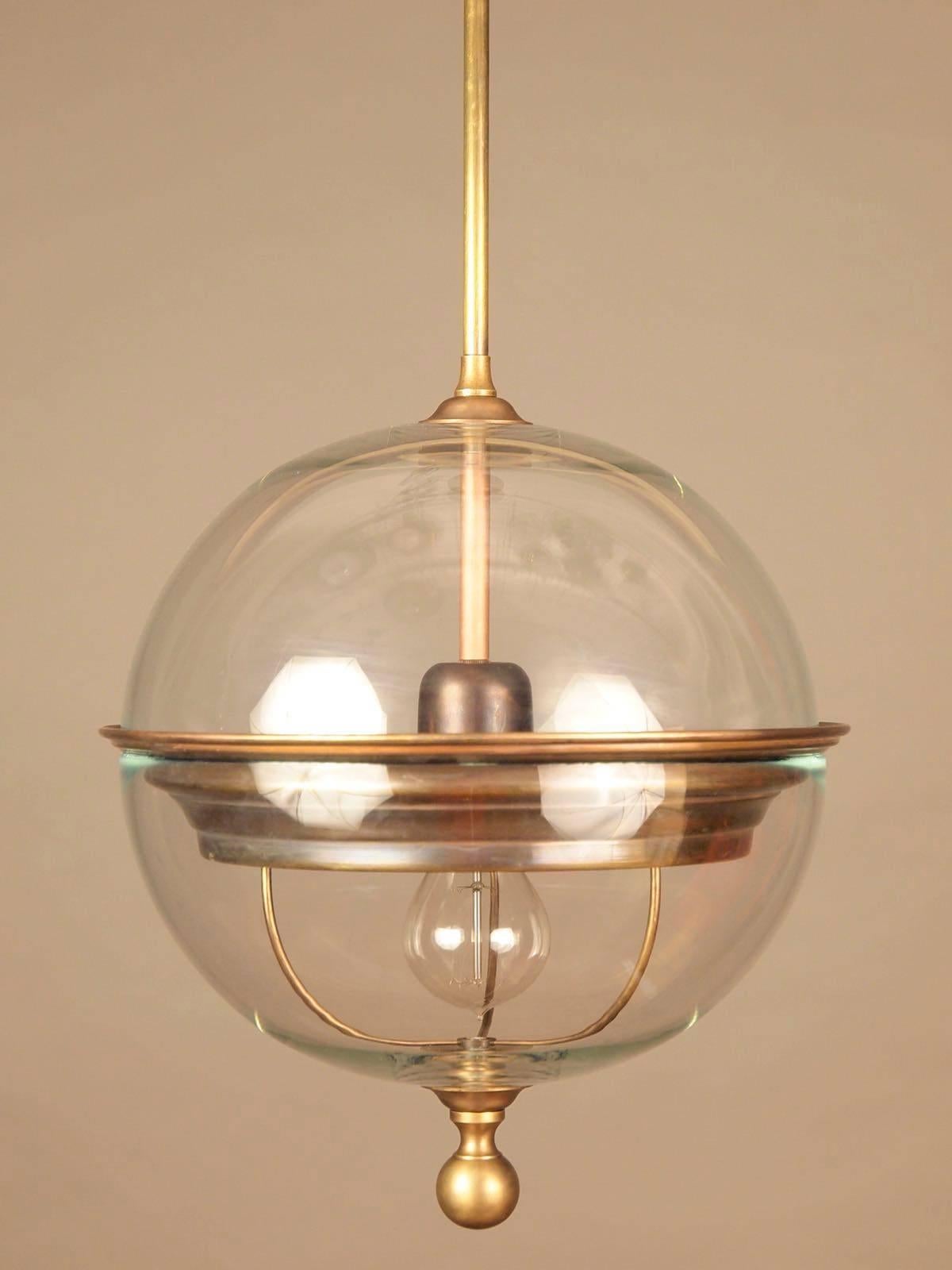 Pair of contemporary Italian glass globe shaped pendants with bronze details.
The globe has a brass finial bottom.
Measures: Globe light fixture height is 13.5