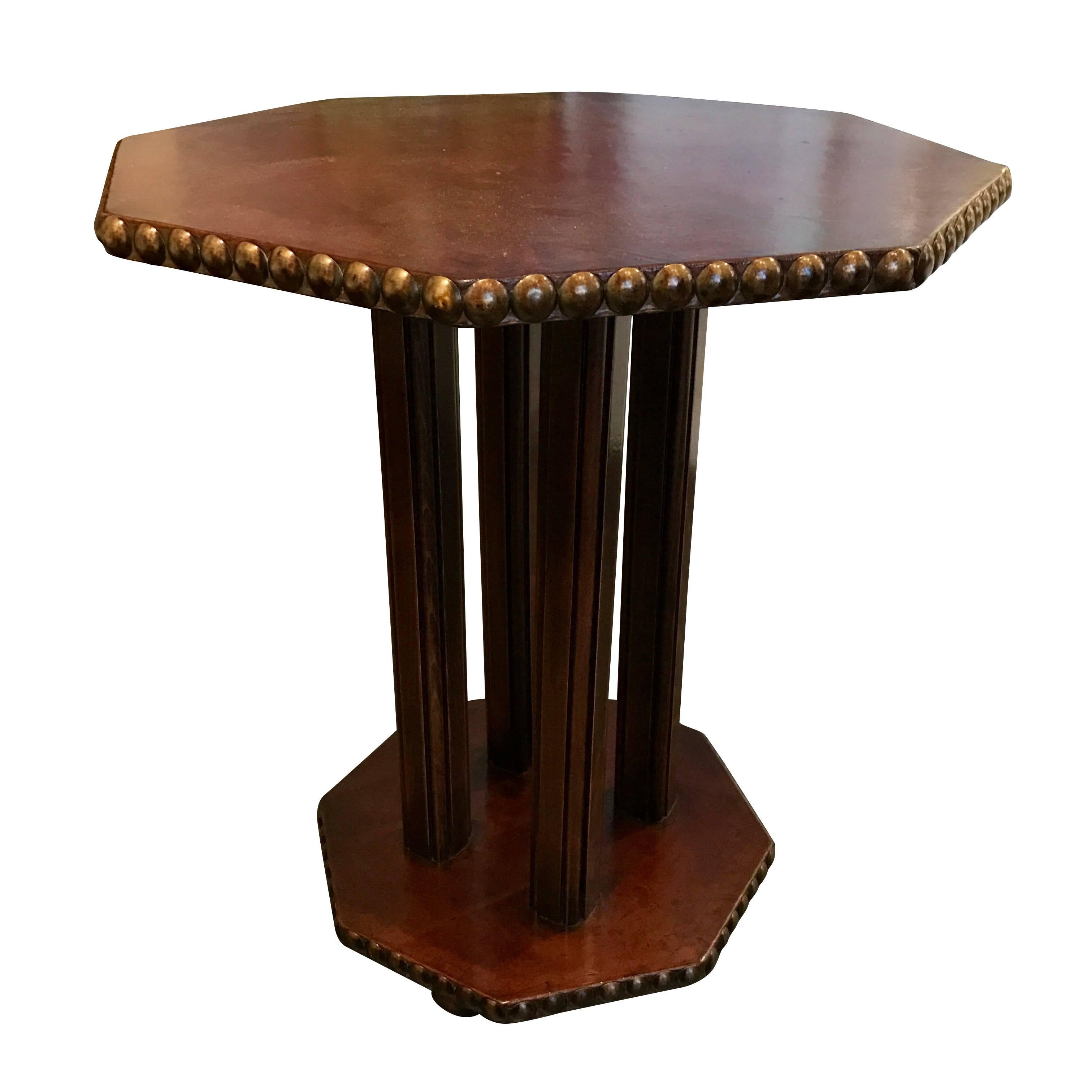 1930s, English octagonally shaped leather top and base side table.
Brass tack details on top and bottom apron.
Four detailed wood column base.