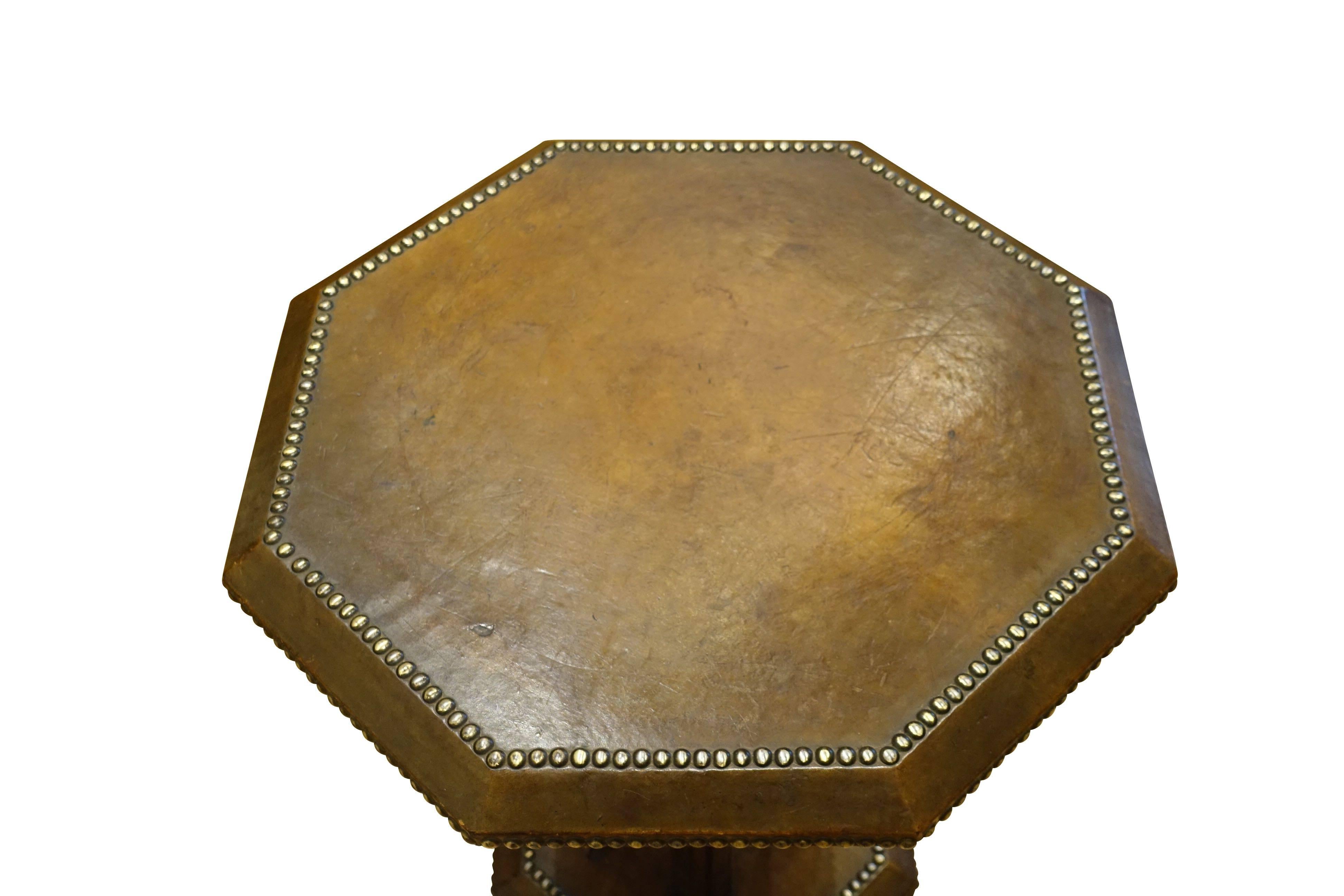 1930s English octagonally shaped brown leather side table with decorative brass tacks.
Two-tiered, leather lower shelf as well. 
Four wooden columns and footed base.
Beautiful leather patina.
 